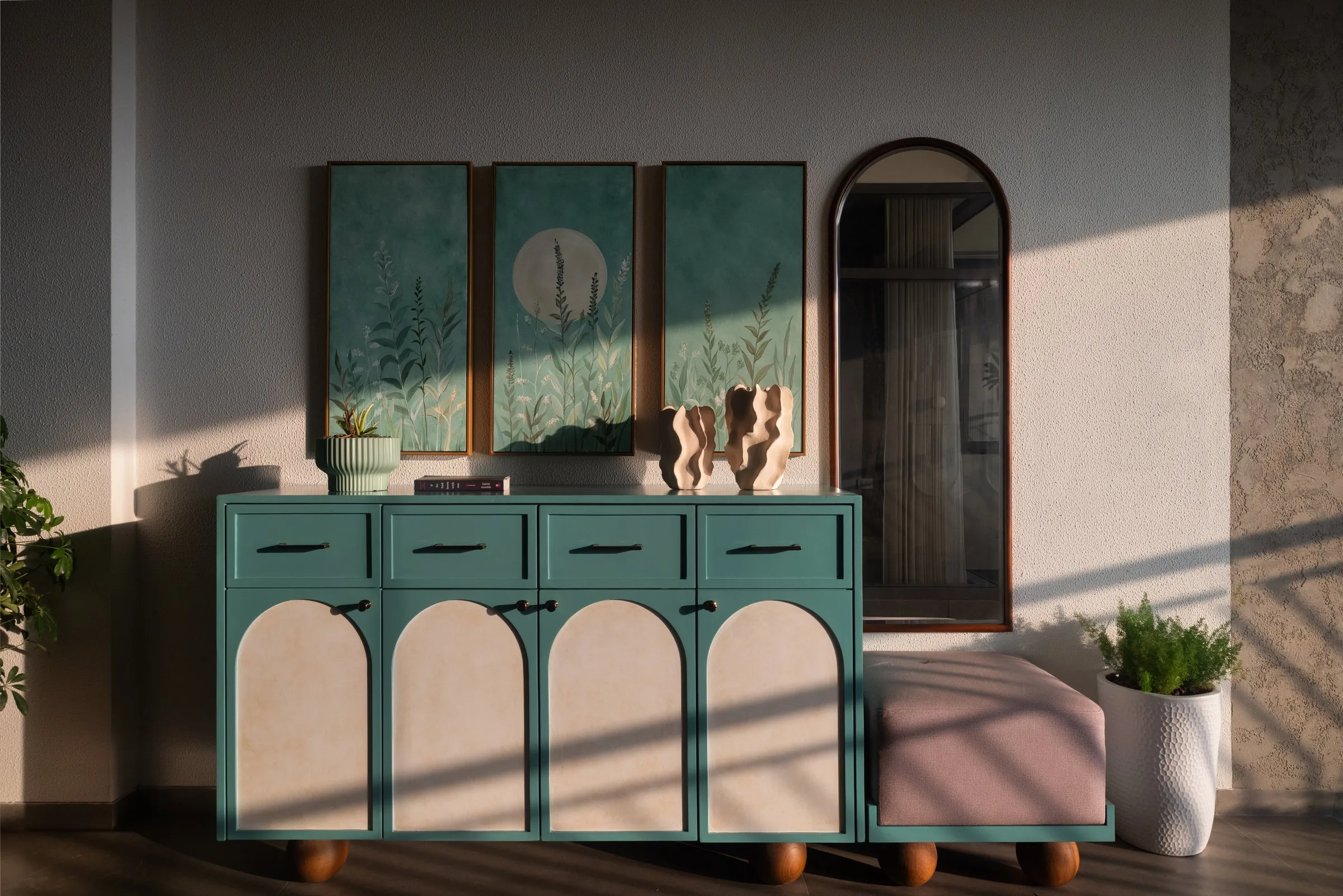 Teal cabinet with arched cane doors and three framed prints