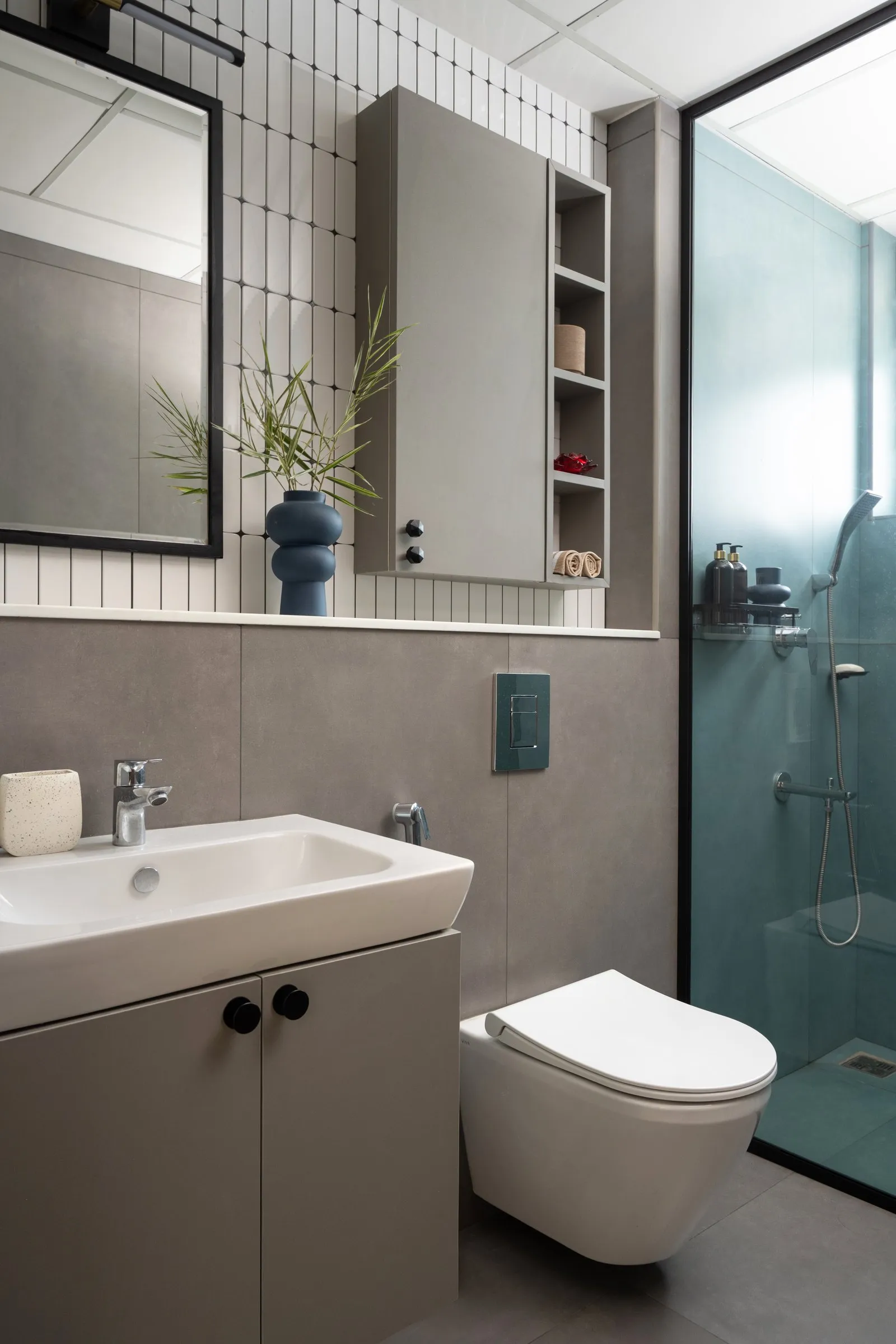 Bathroom with a grey vanity and a teal glass shower