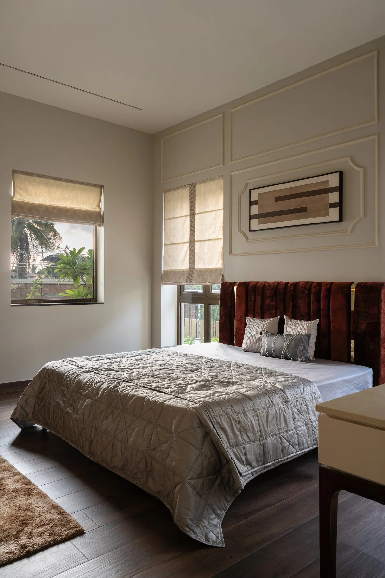 Main bedroom with a red velvet headboard and silver quilt