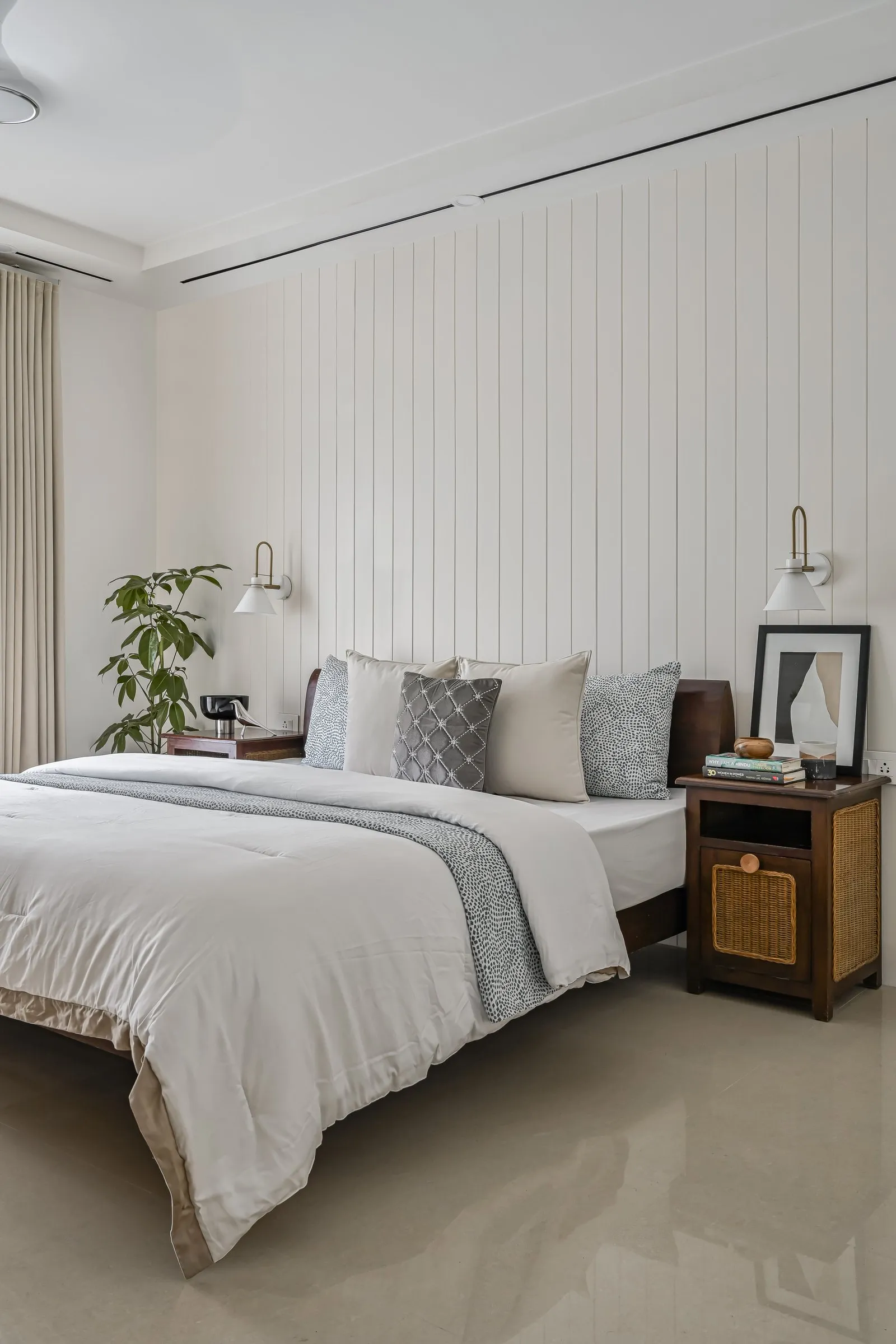 Bedroom with a white panelled wall and a rattan bedside table