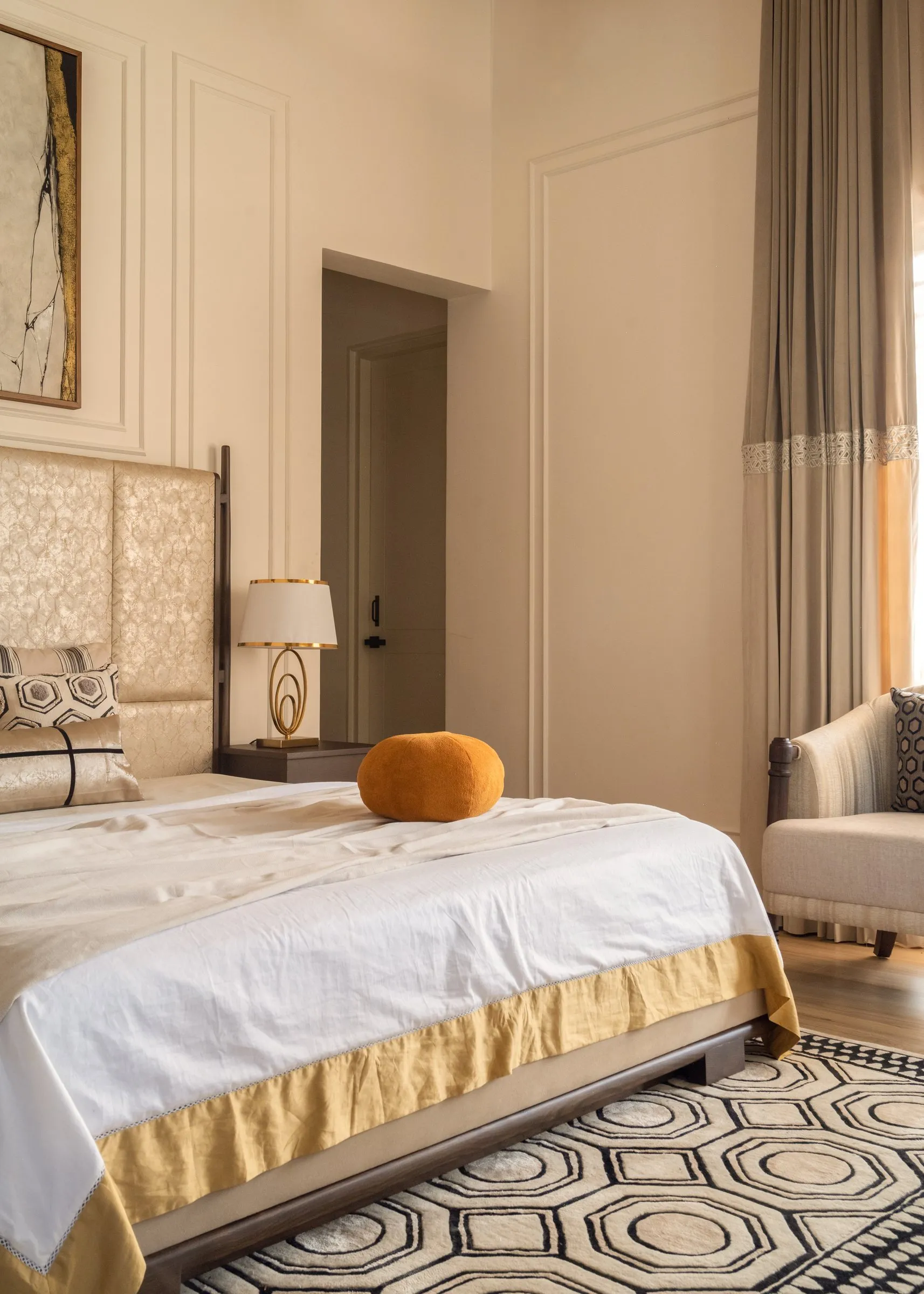 Main bedroom with gold-trimmed bedding and a mustard cushion