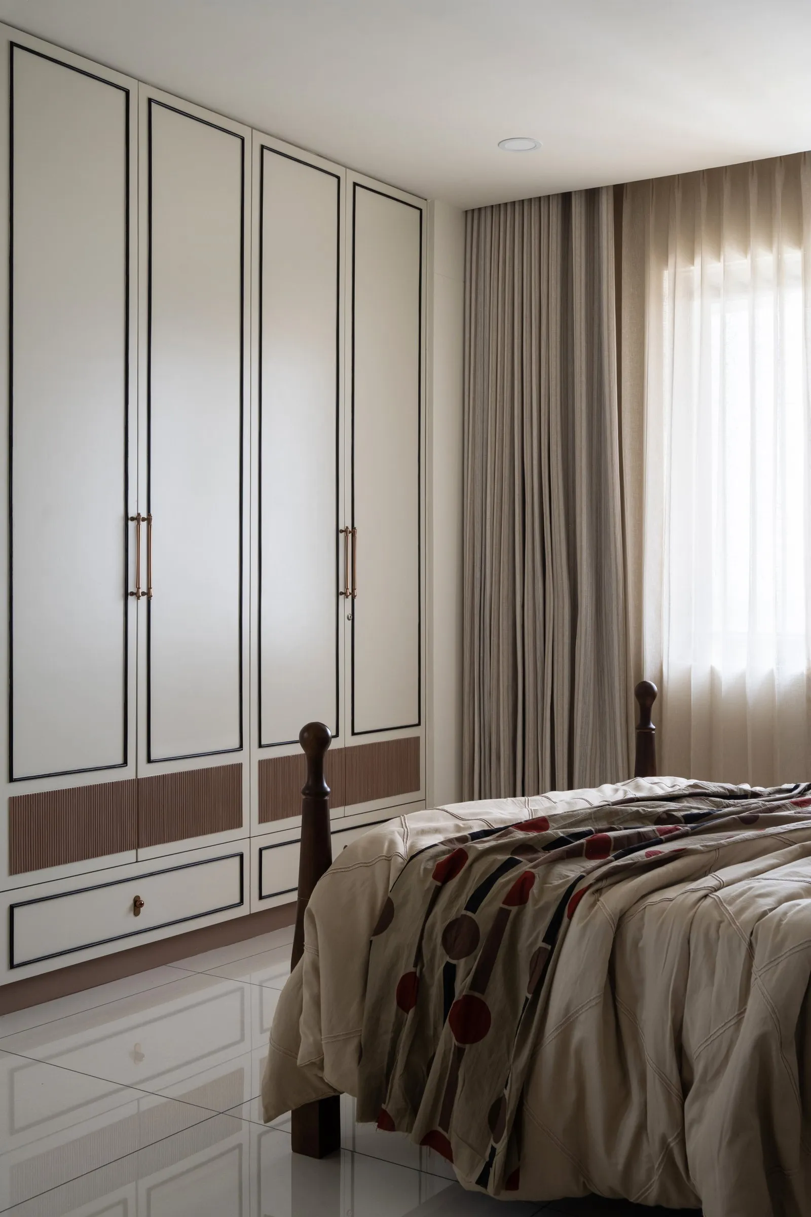 White wardrobe with slim brass handles beside the bed