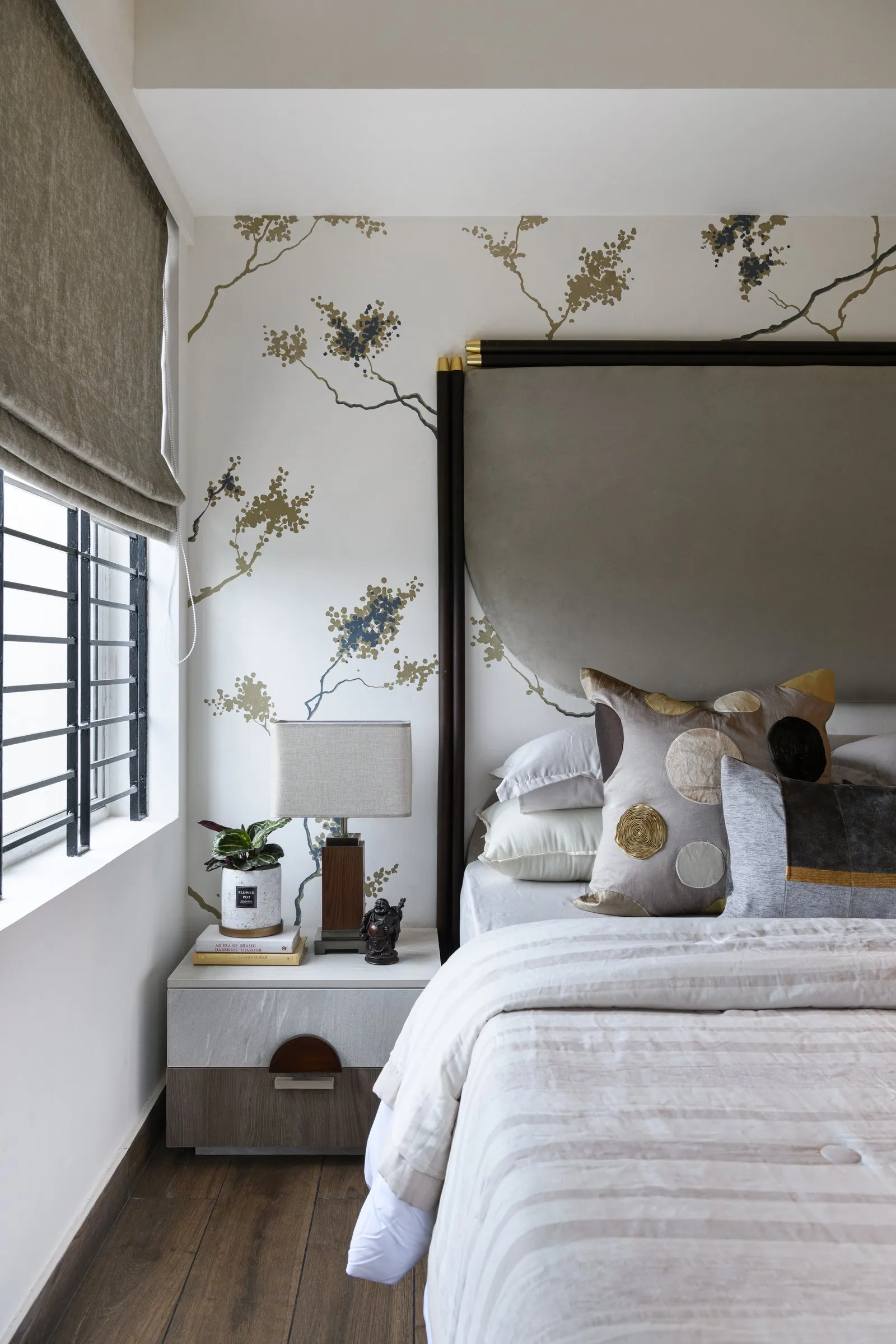 Bed with a tall grey headboard and painted branches