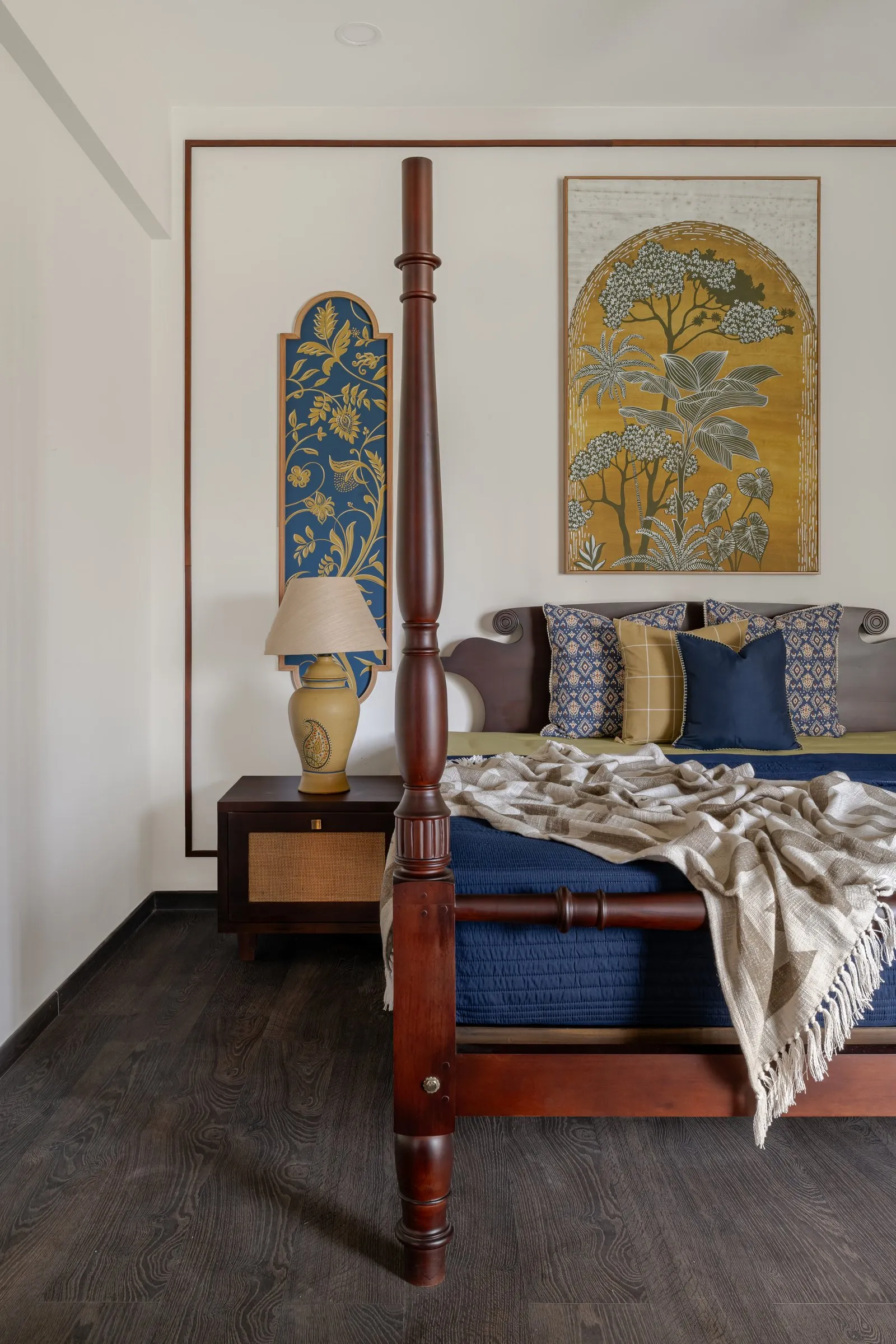 Teak four-poster bed with indigo bedding and a painted panel