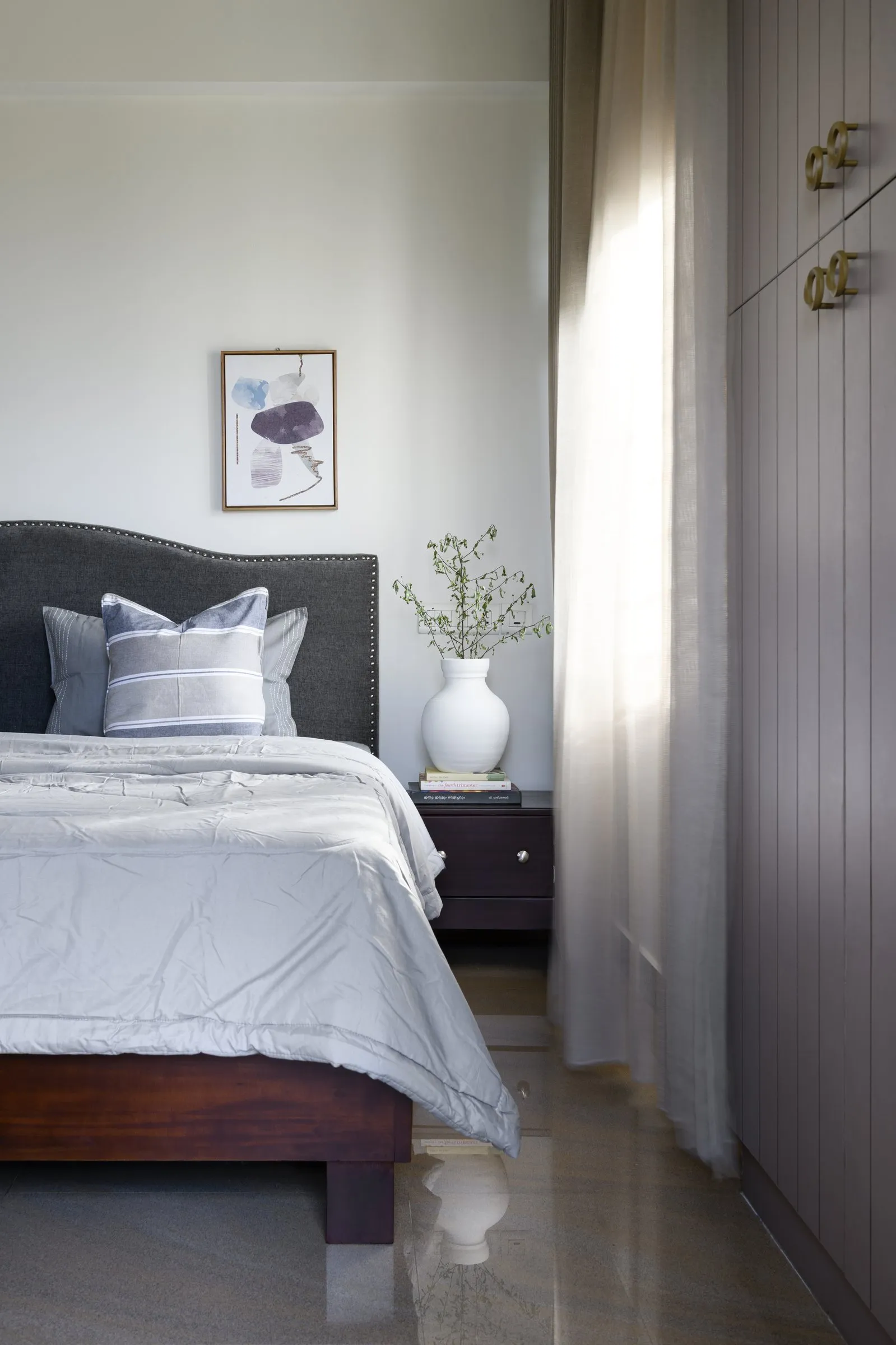 Bedroom with a grey headboard and a tall wardrobe