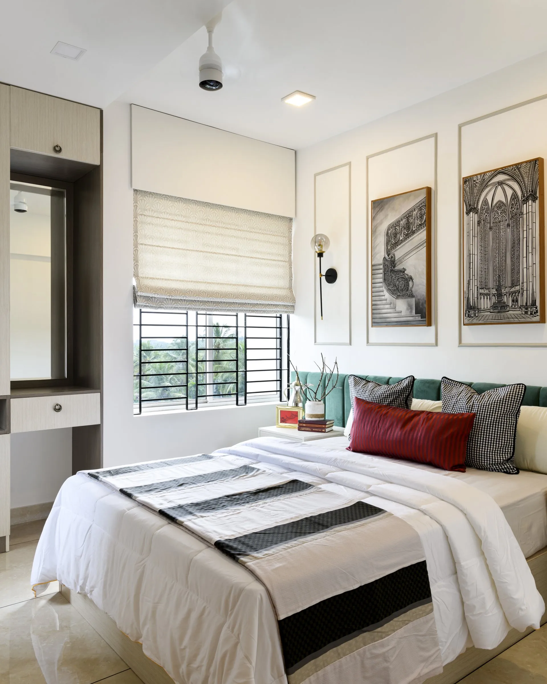 Bedroom with a red cushion and framed architectural prints