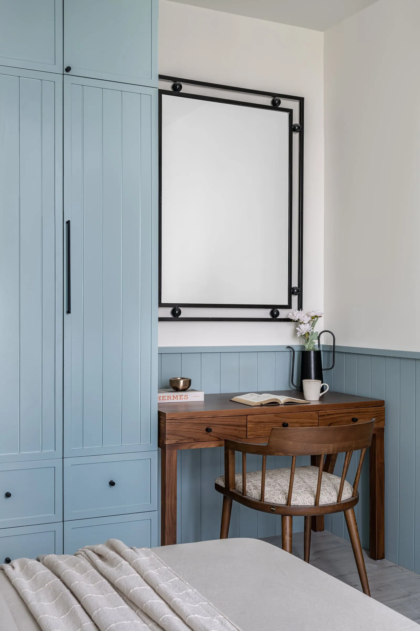 Powder-blue wardrobe beside a walnut study desk
