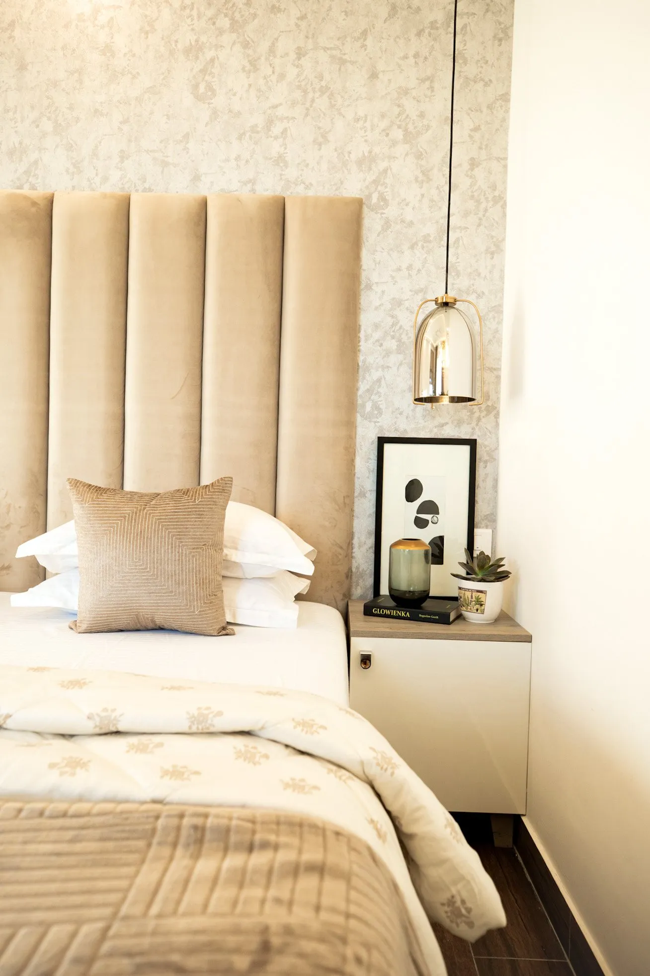 Bed with a cream quilt and gold cushion