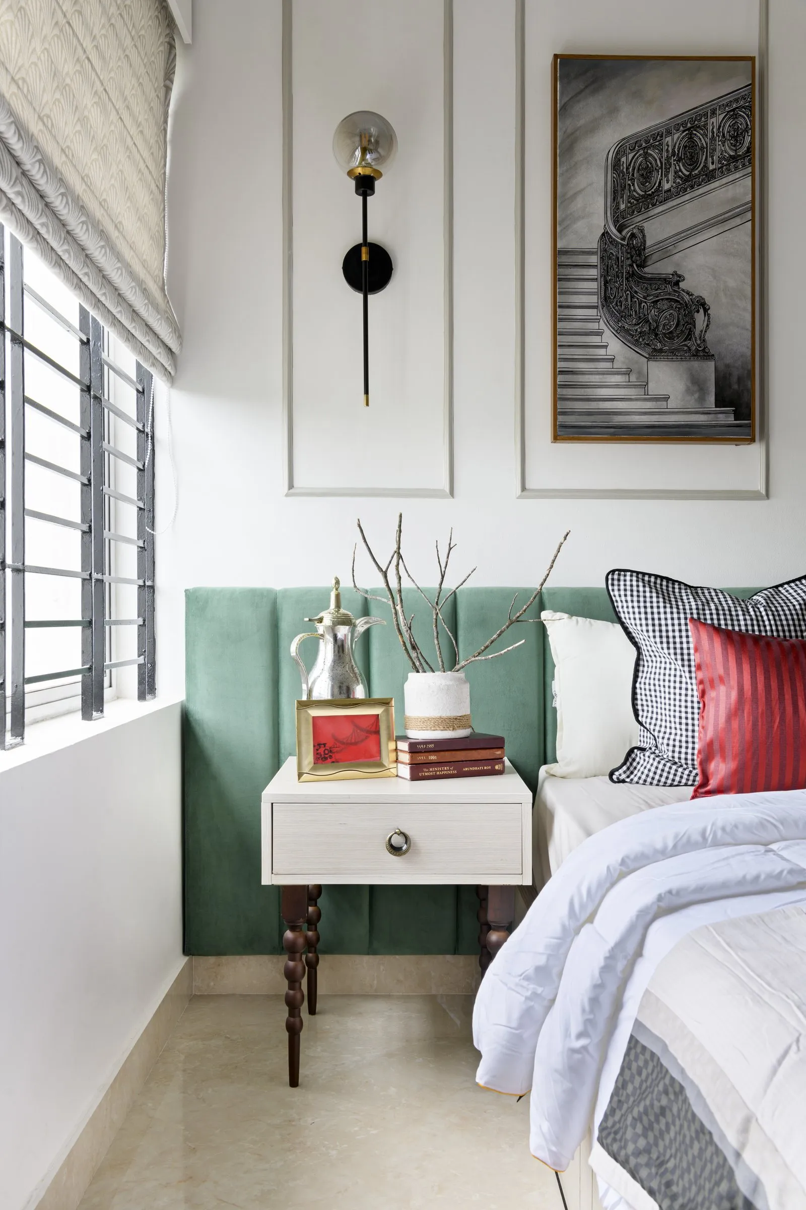 Green padded headboard with a wall light and a bedside table
