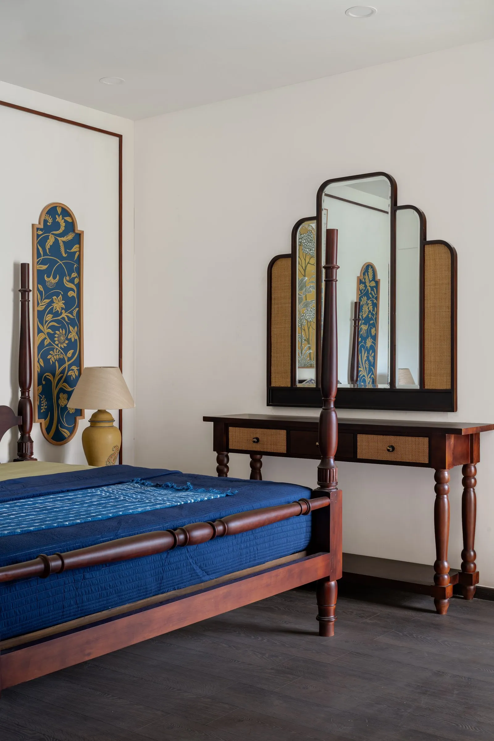 Four-poster bed beside a cane dressing table with a tall mirror