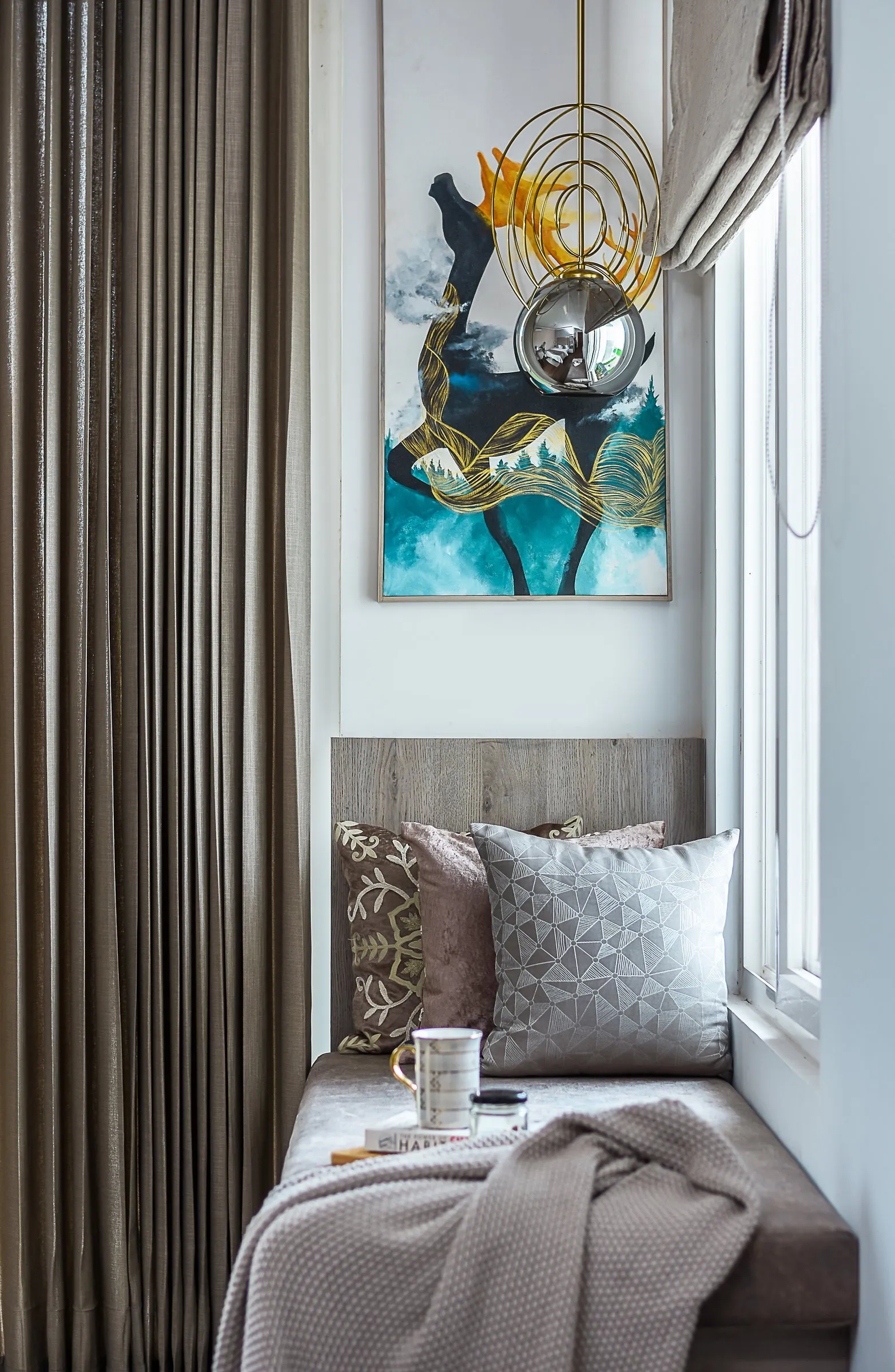 Window seat with grey cushions and an abstract painting