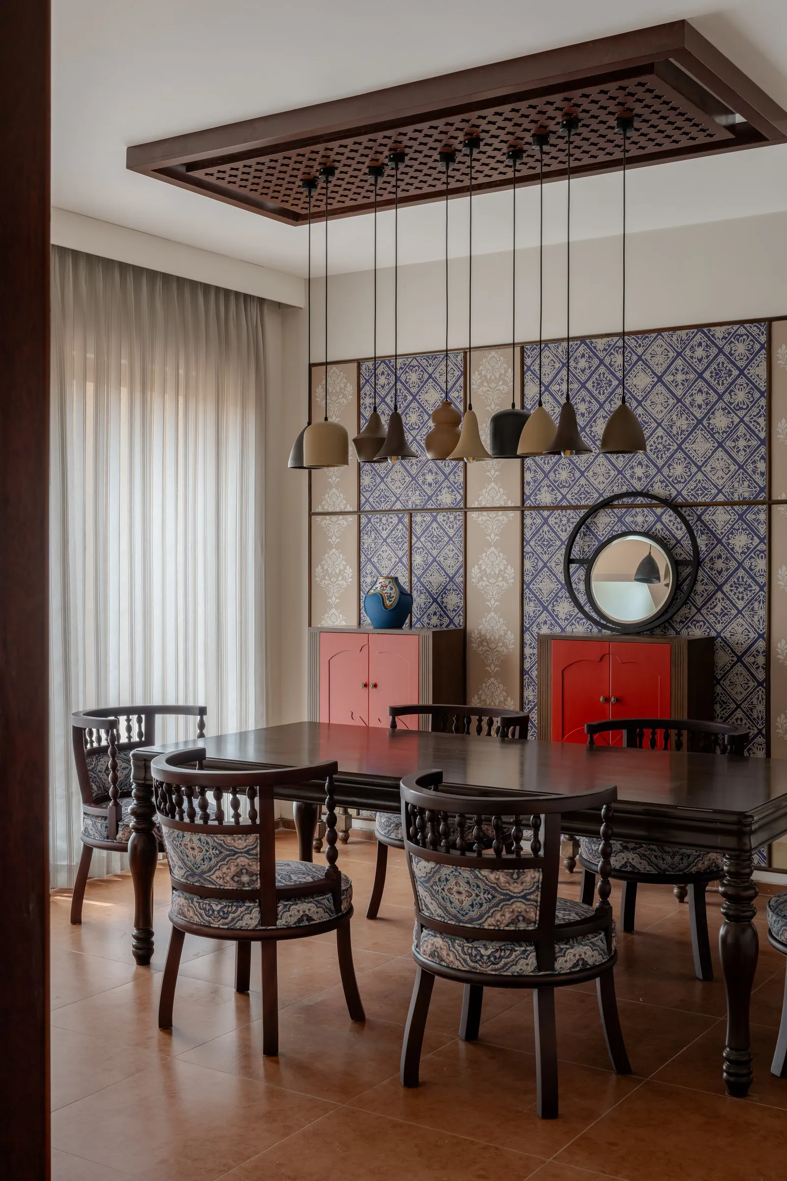 Dining room with blue patterned wall panels, red cabinets and a cluster of pendant lights