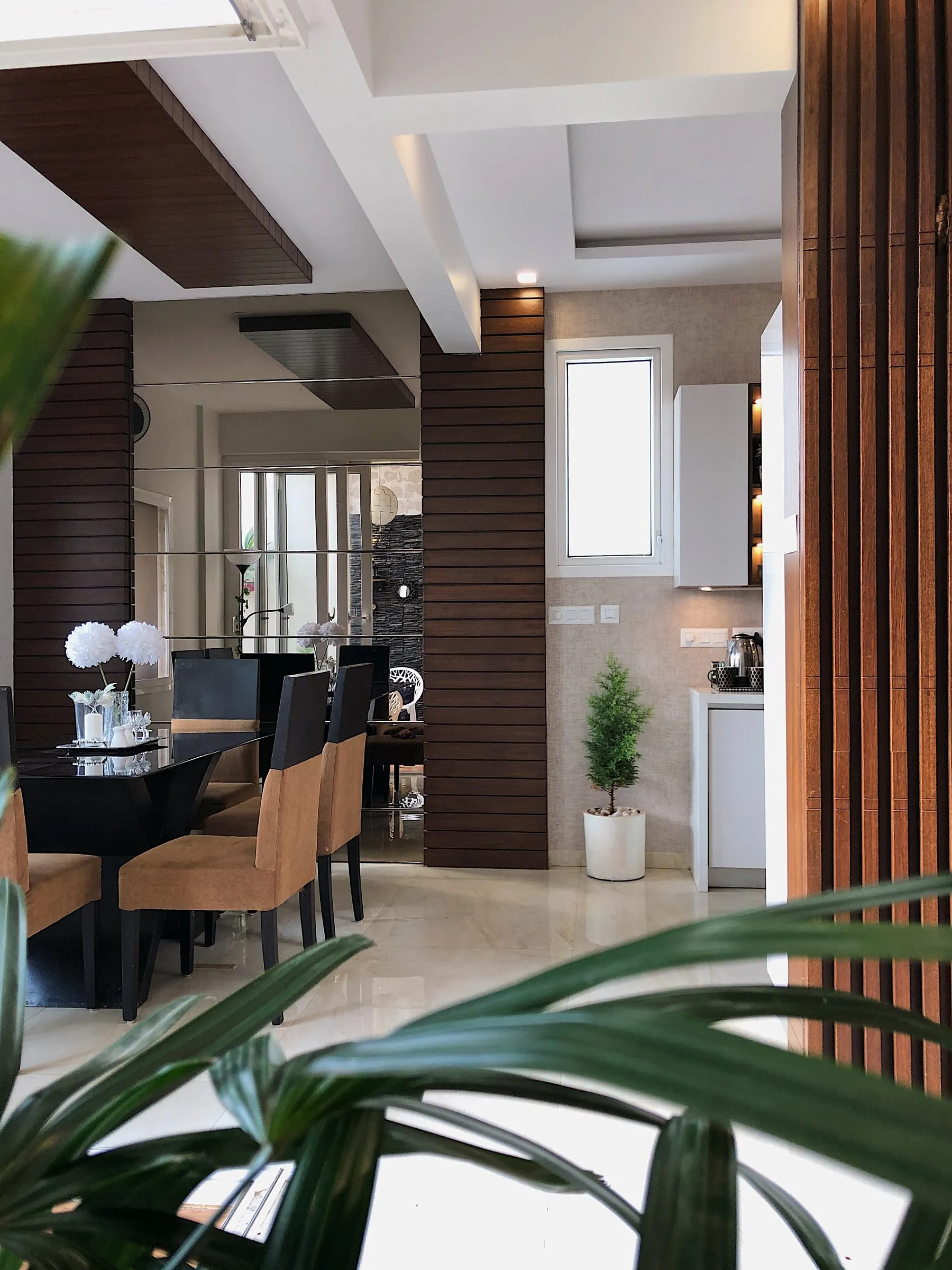 Dining room seen past wooden slat walls and plants