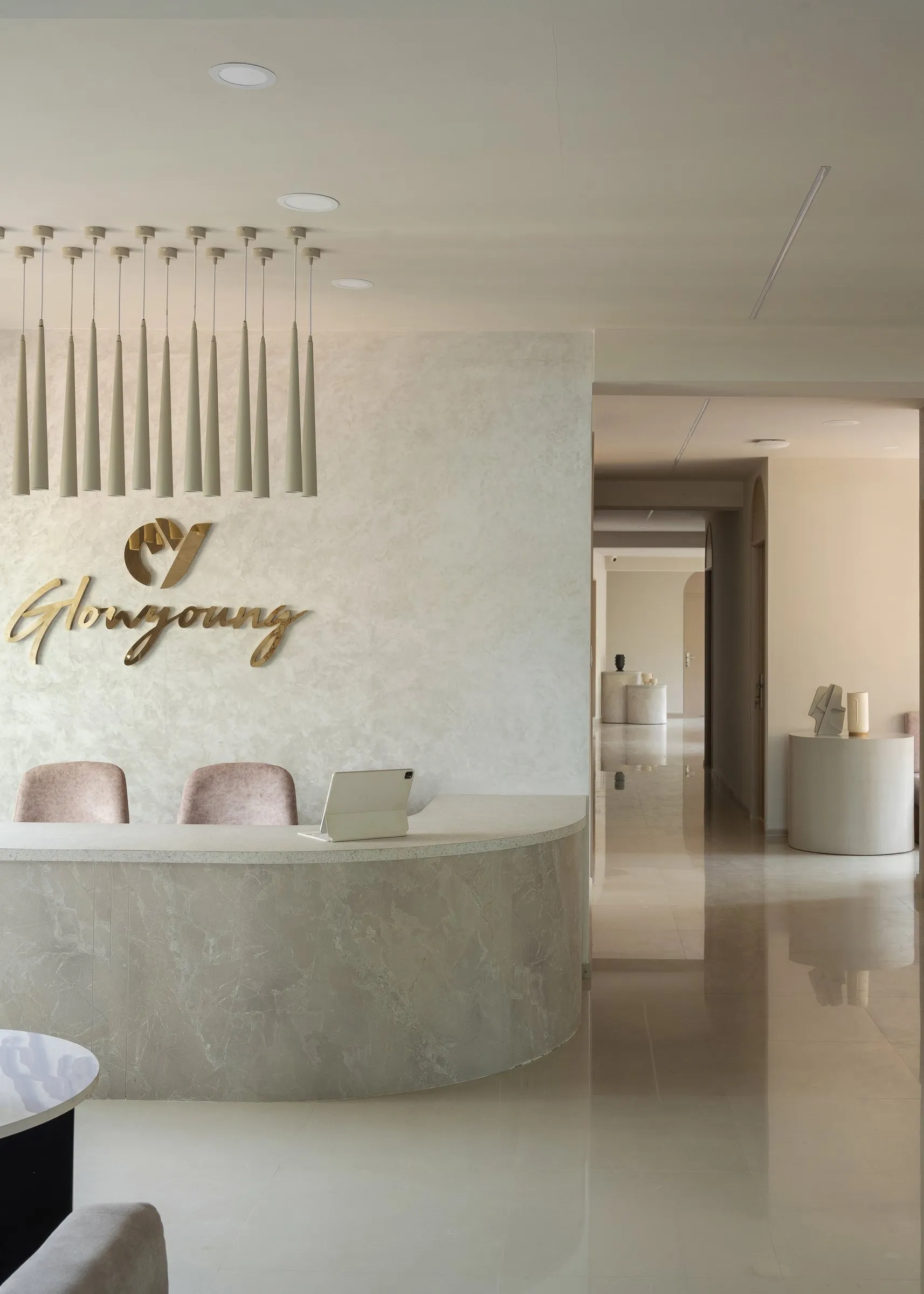 Clinic reception with a curved stone desk and gold lettering, looking down the corridor
