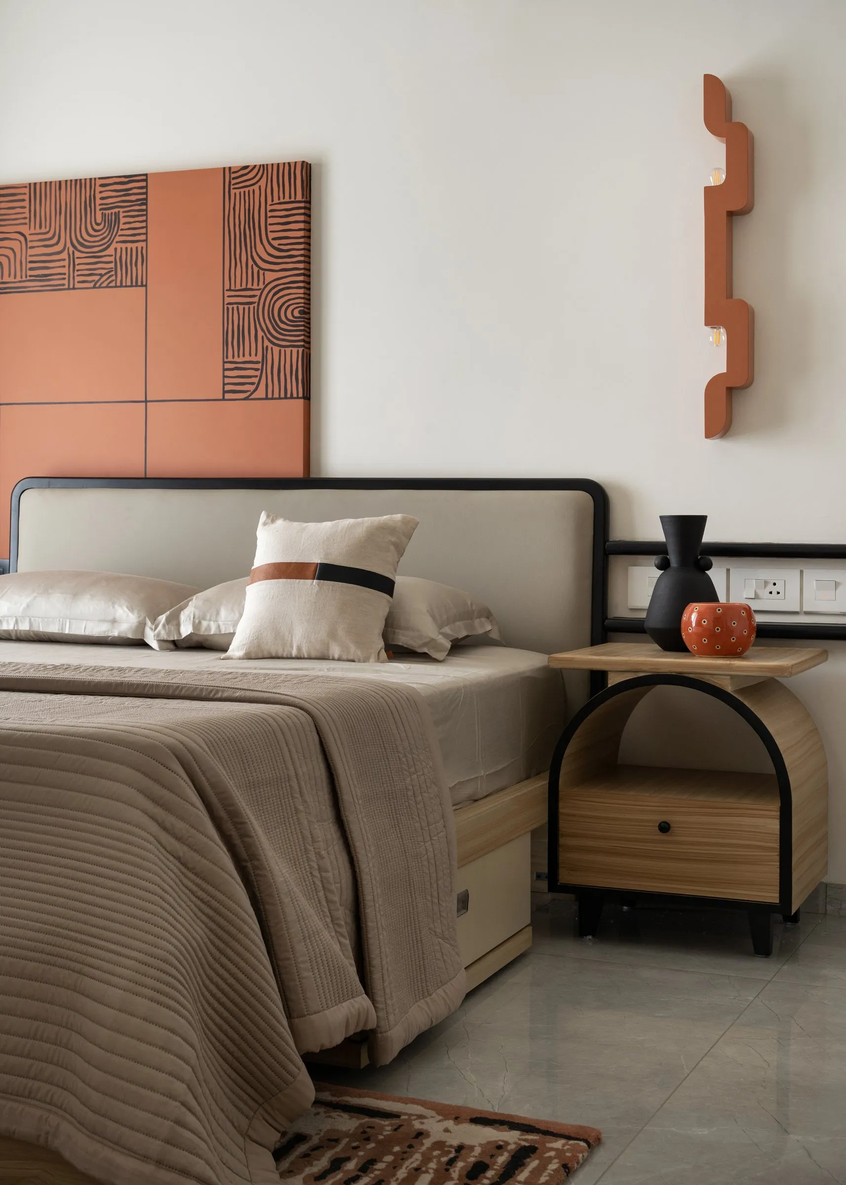 Rust wall panel and sculpted wall light above a bed