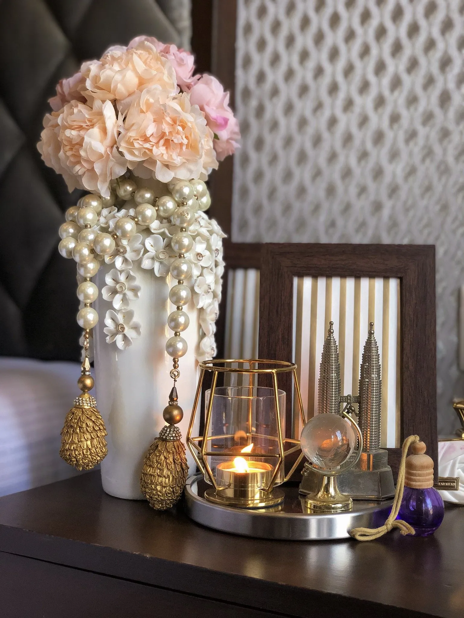 Pearl-draped vase with roses and a gold candle holder