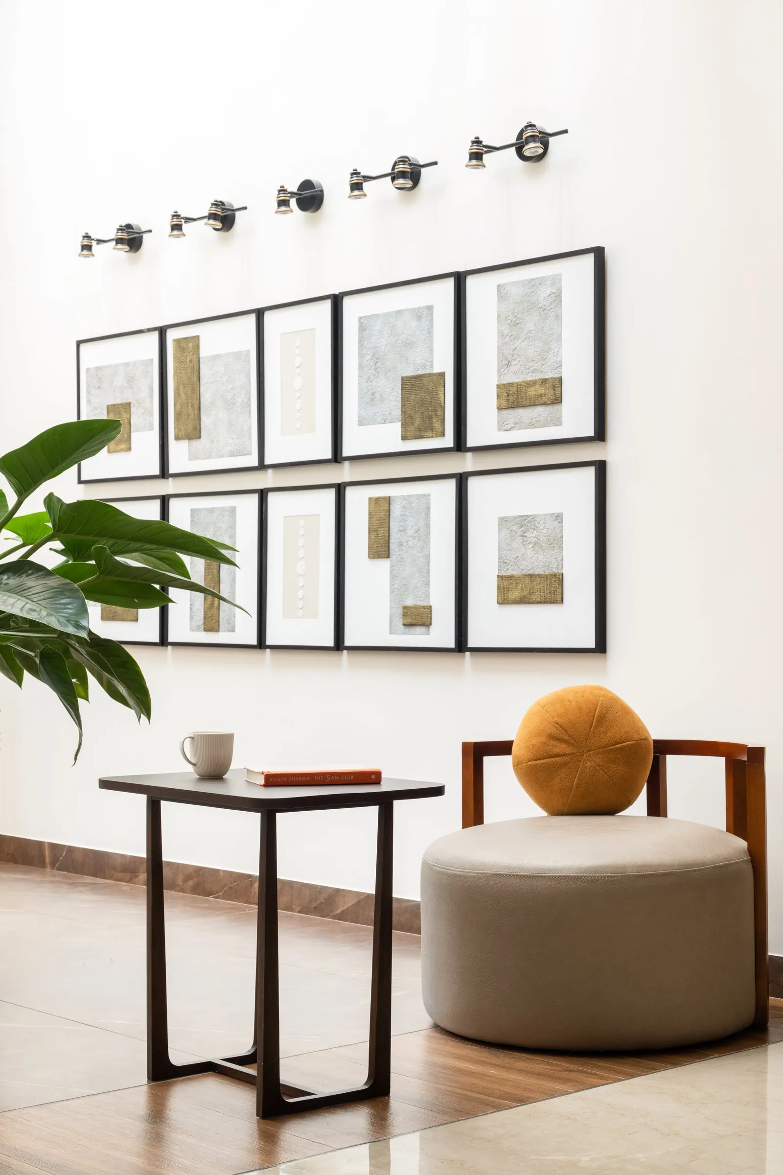 Gallery wall of framed prints with a round mustard-cushion stool