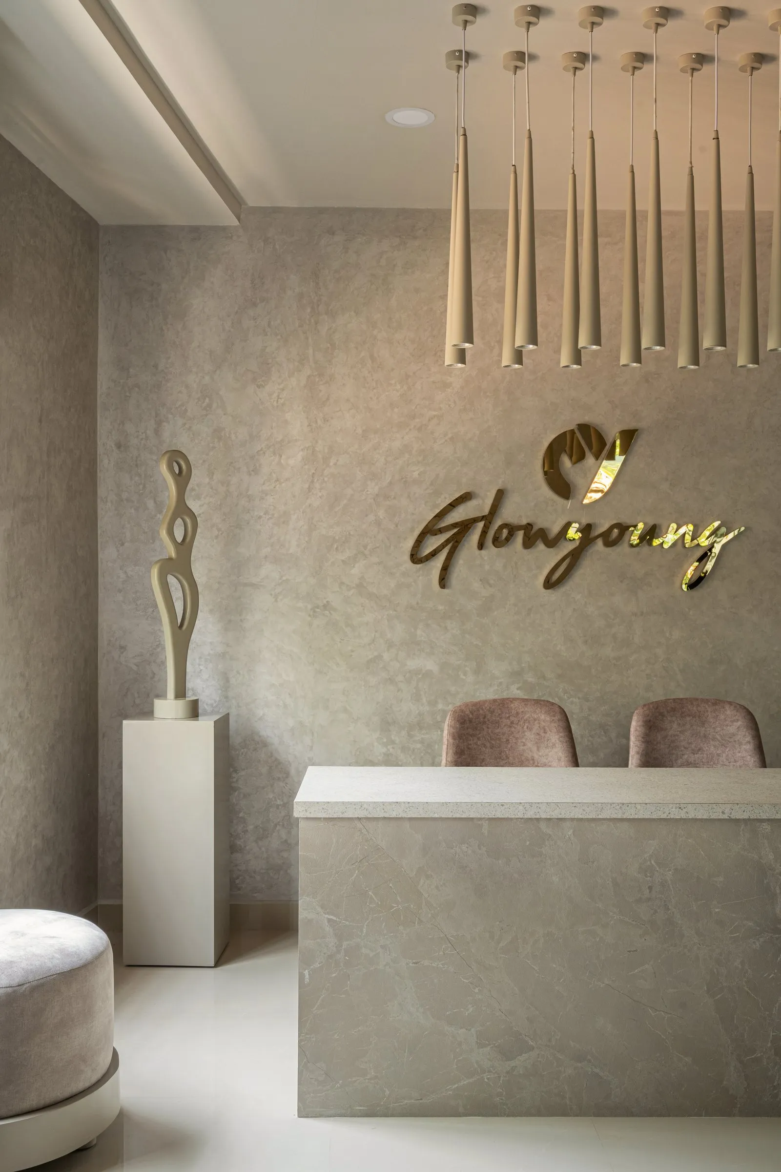 Gold logo on a textured wall with a sculpture on a stone plinth