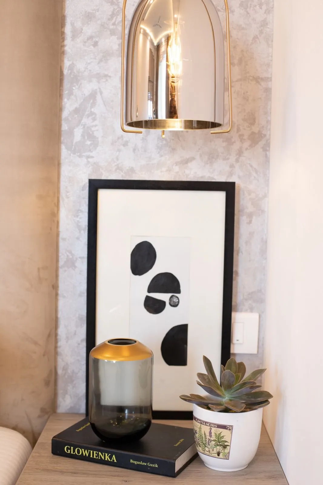 Smoked glass pendant over a bedside with black and white art