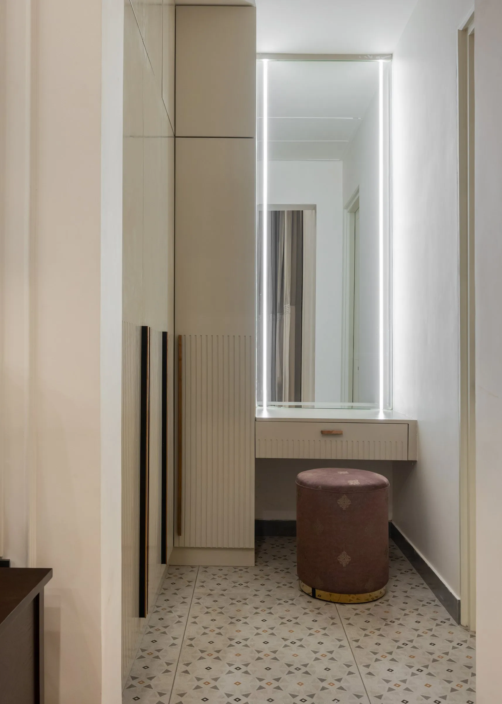 Dressing area with a lit mirror and pink velvet stool