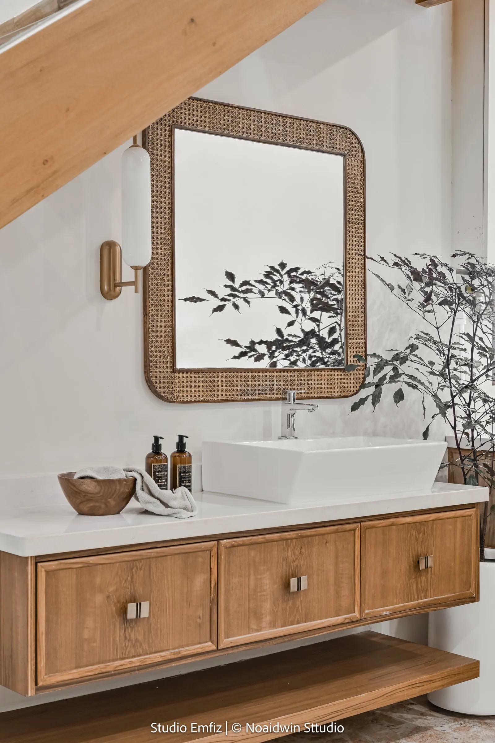 Cane mirror and brass wall light over an oak vanity
