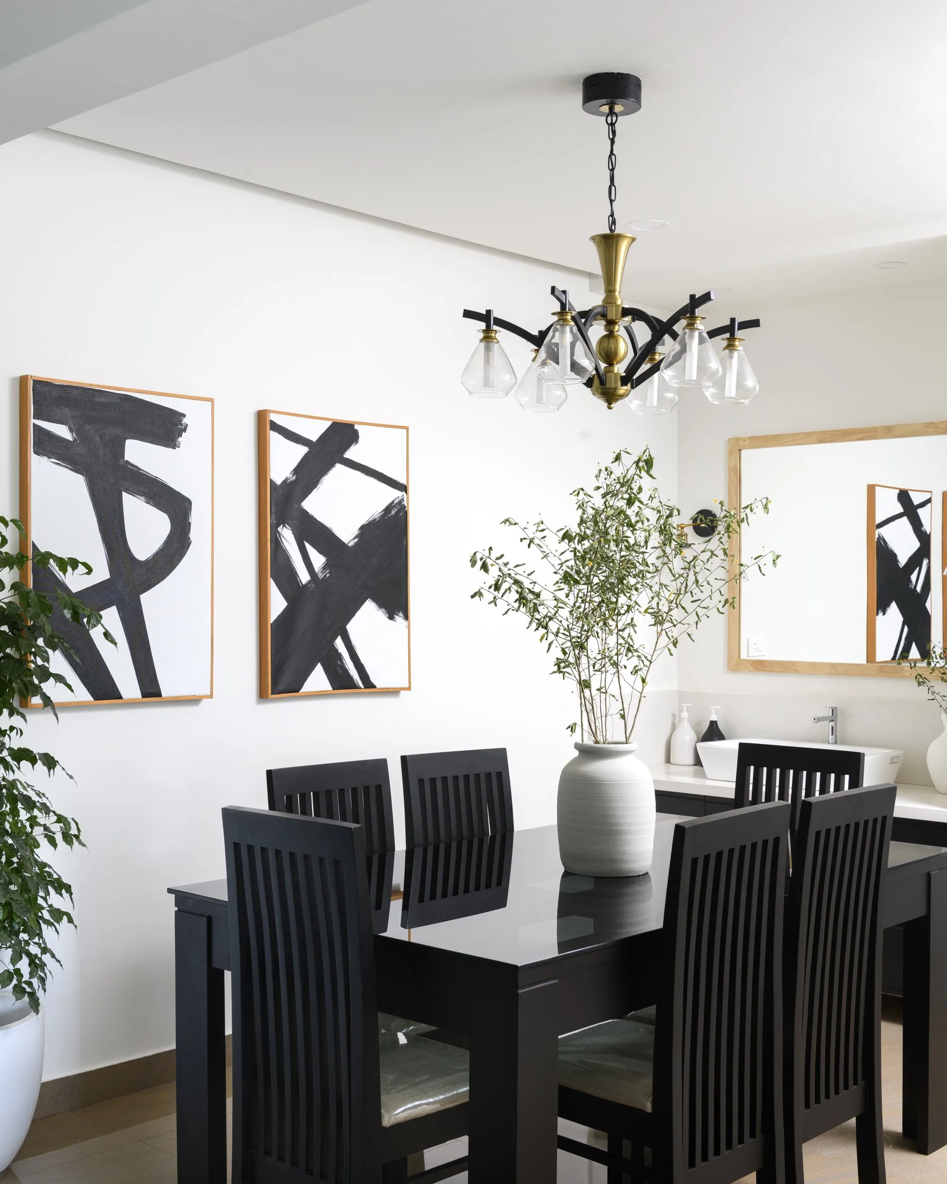 Black dining table with a brass chandelier and bold black and white art