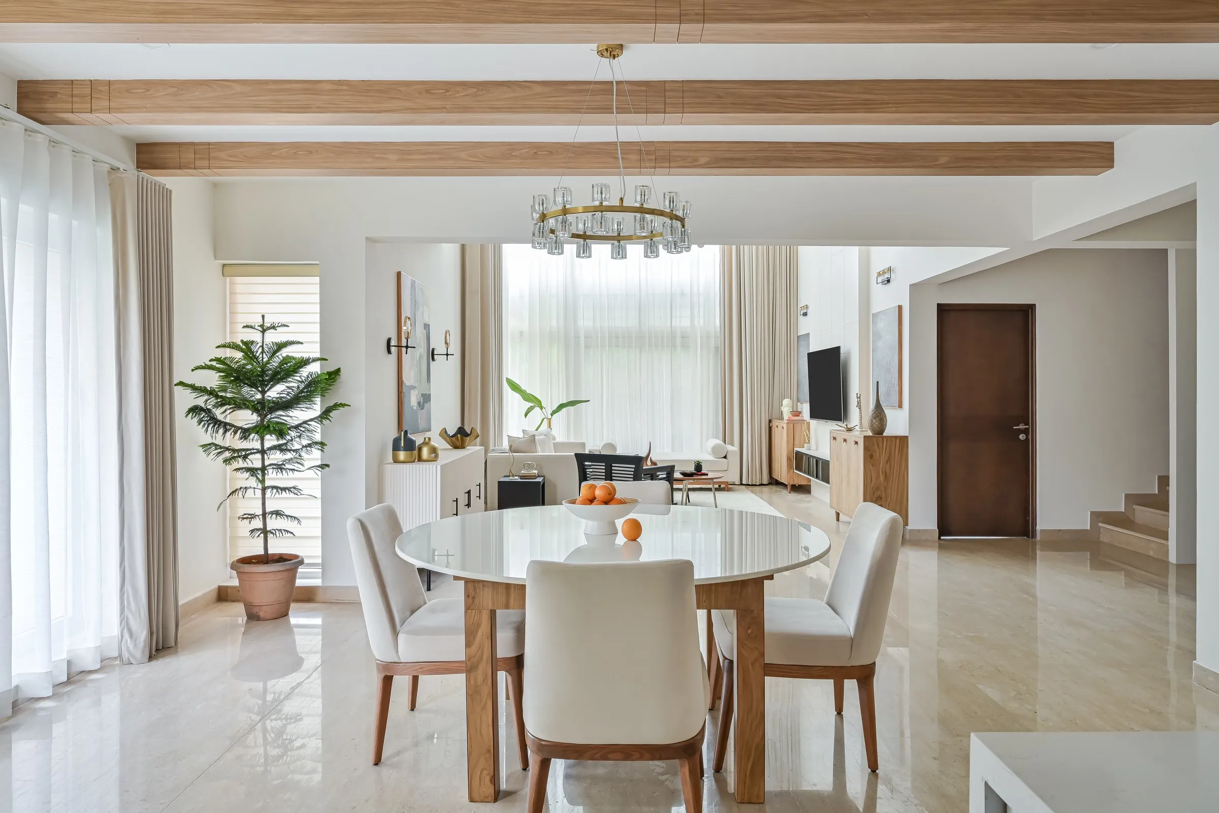 Dining area under oak beams with tall windows behind