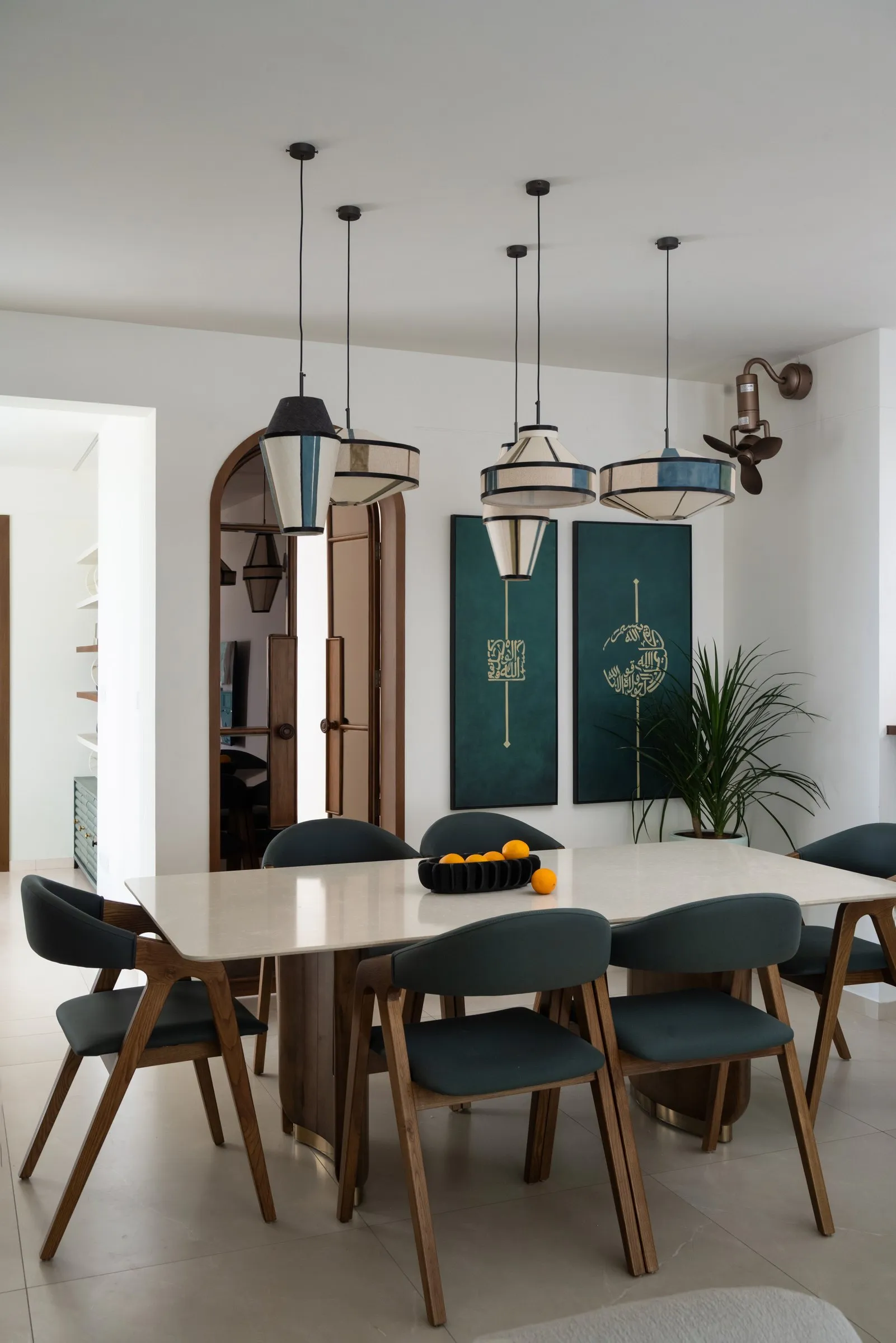 Dining table with teal chairs and green artwork on the wall