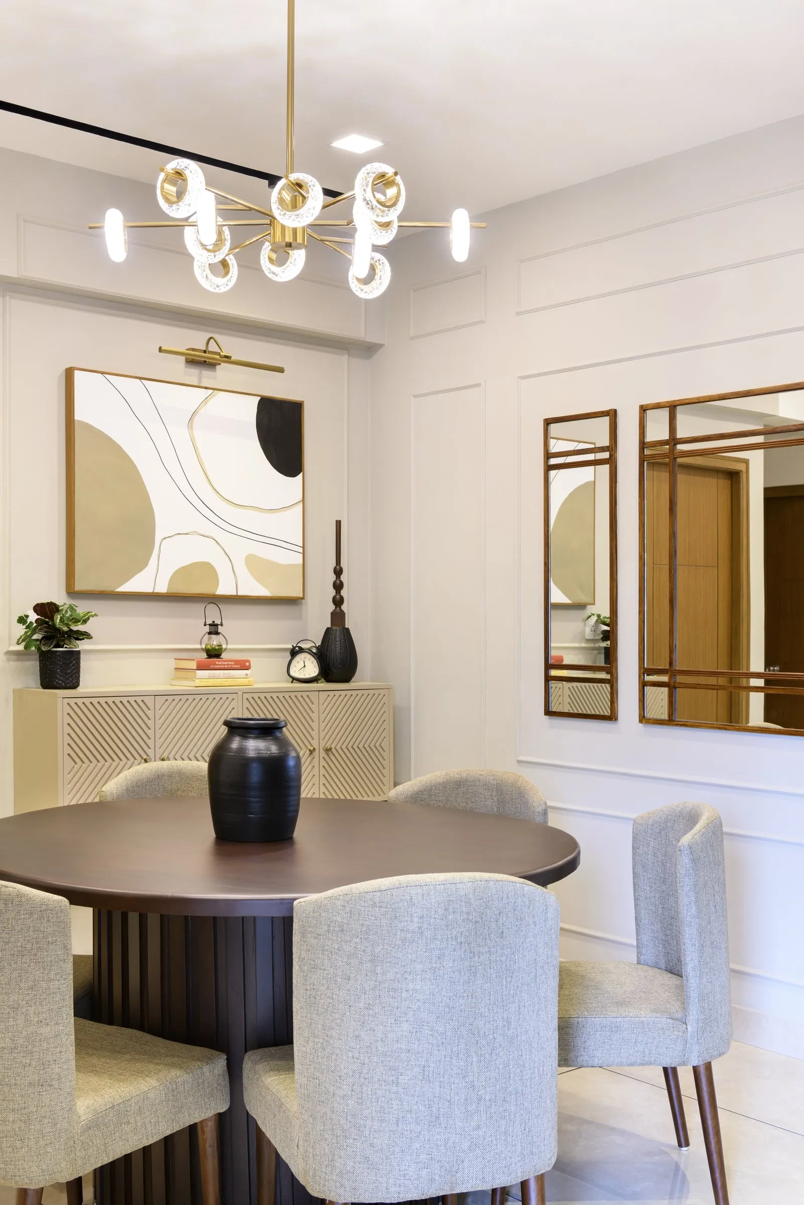 Round dining table with cream chairs and a gold chandelier