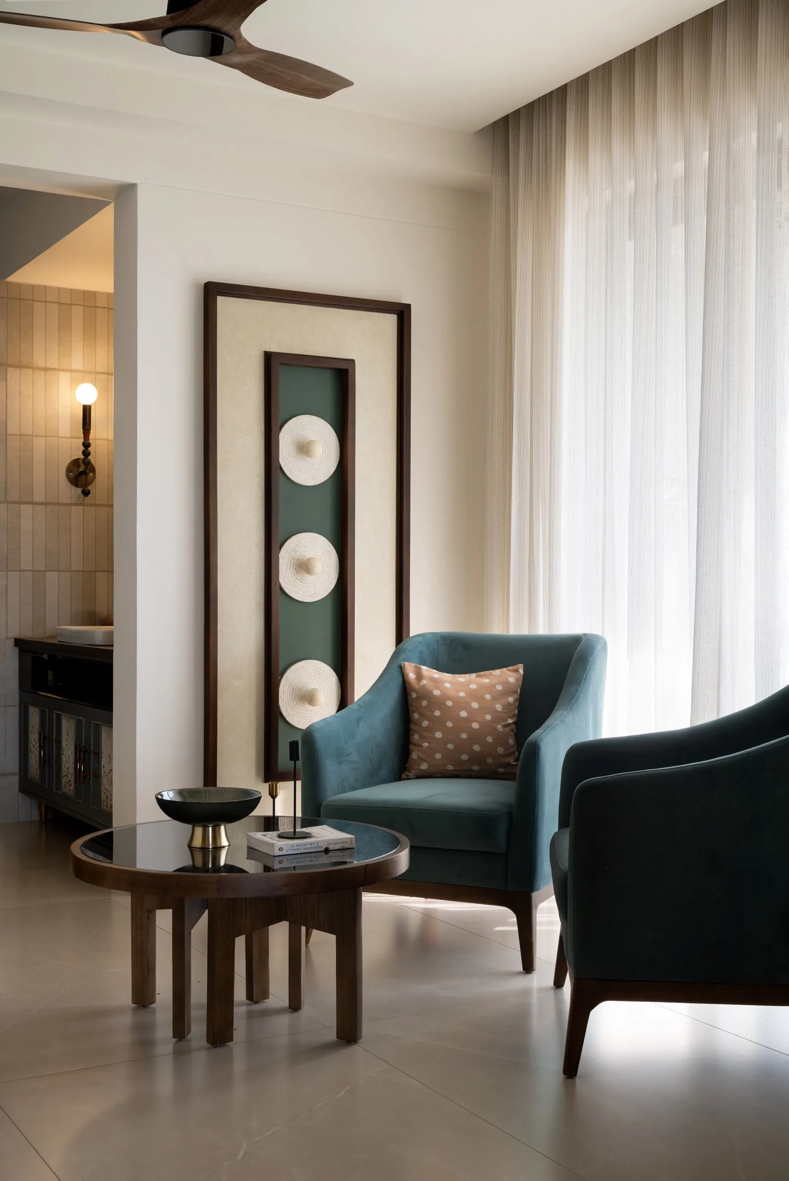Teal armchairs around a round walnut table in the family living room