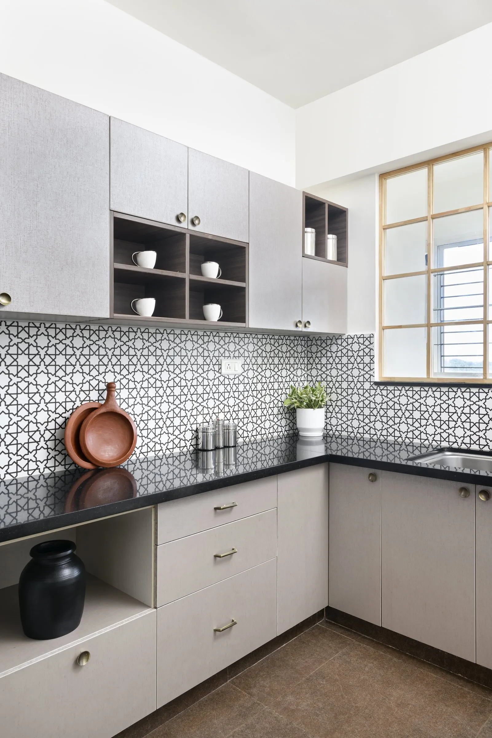 Grey kitchen with a black counter and patterned tile backsplash