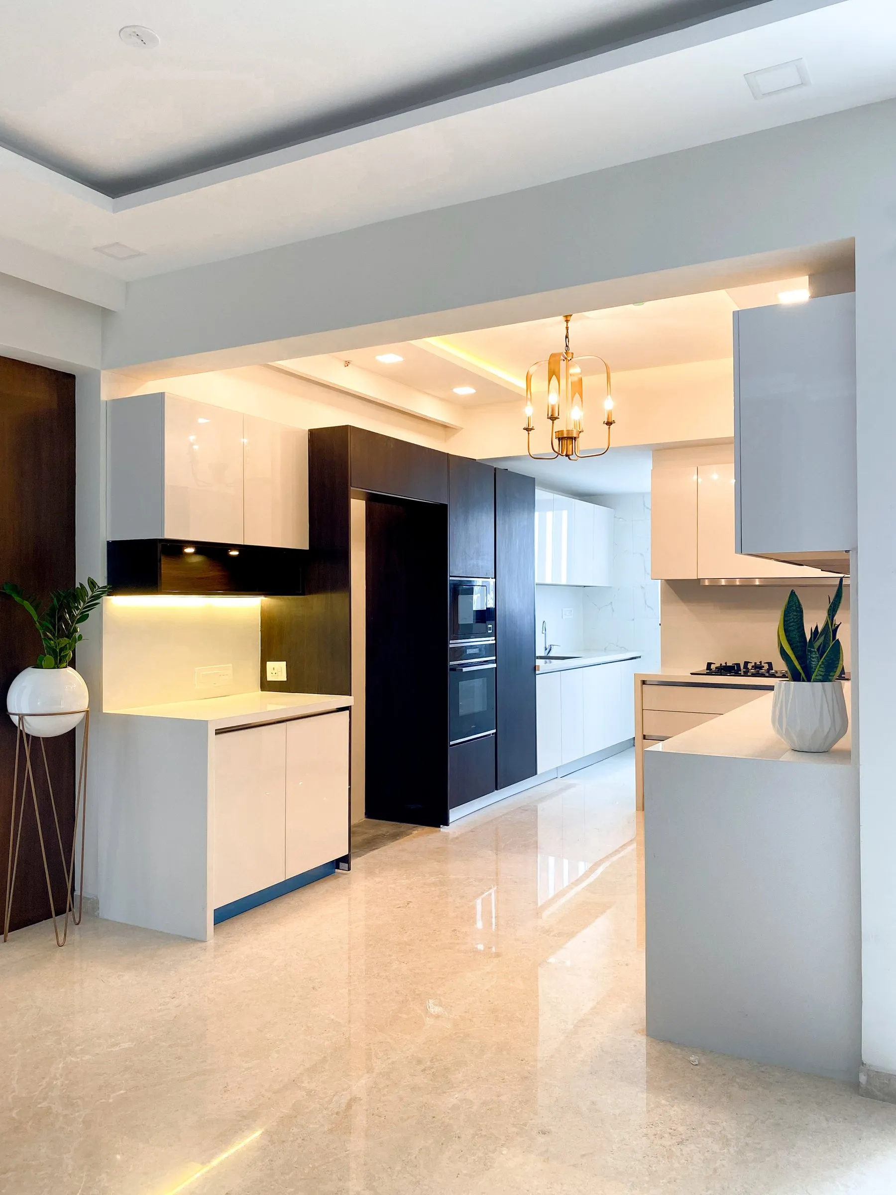 Open kitchen with white and black cabinets and a gold chandelier