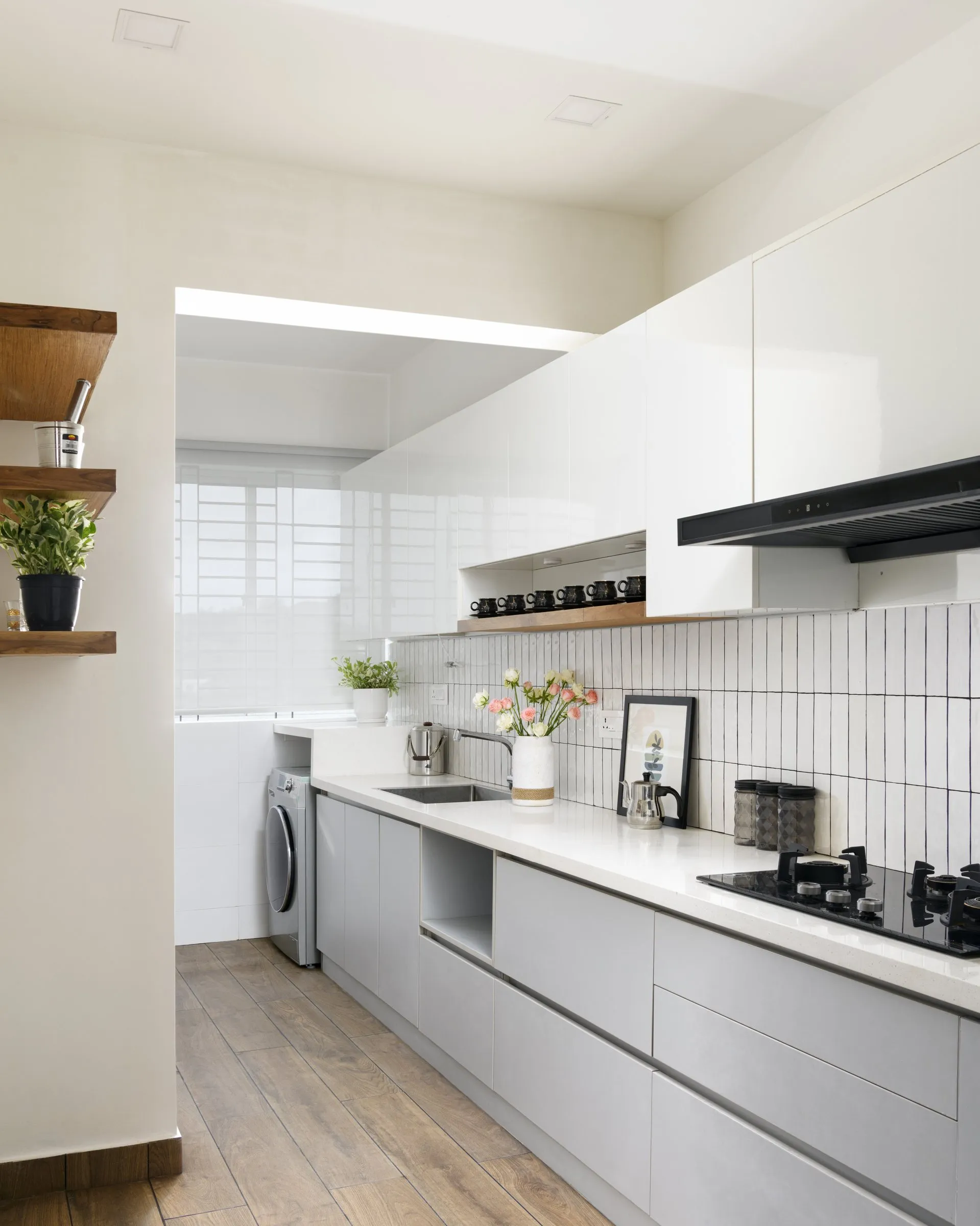 Galley kitchen with white gloss cabinets and a tiled wall