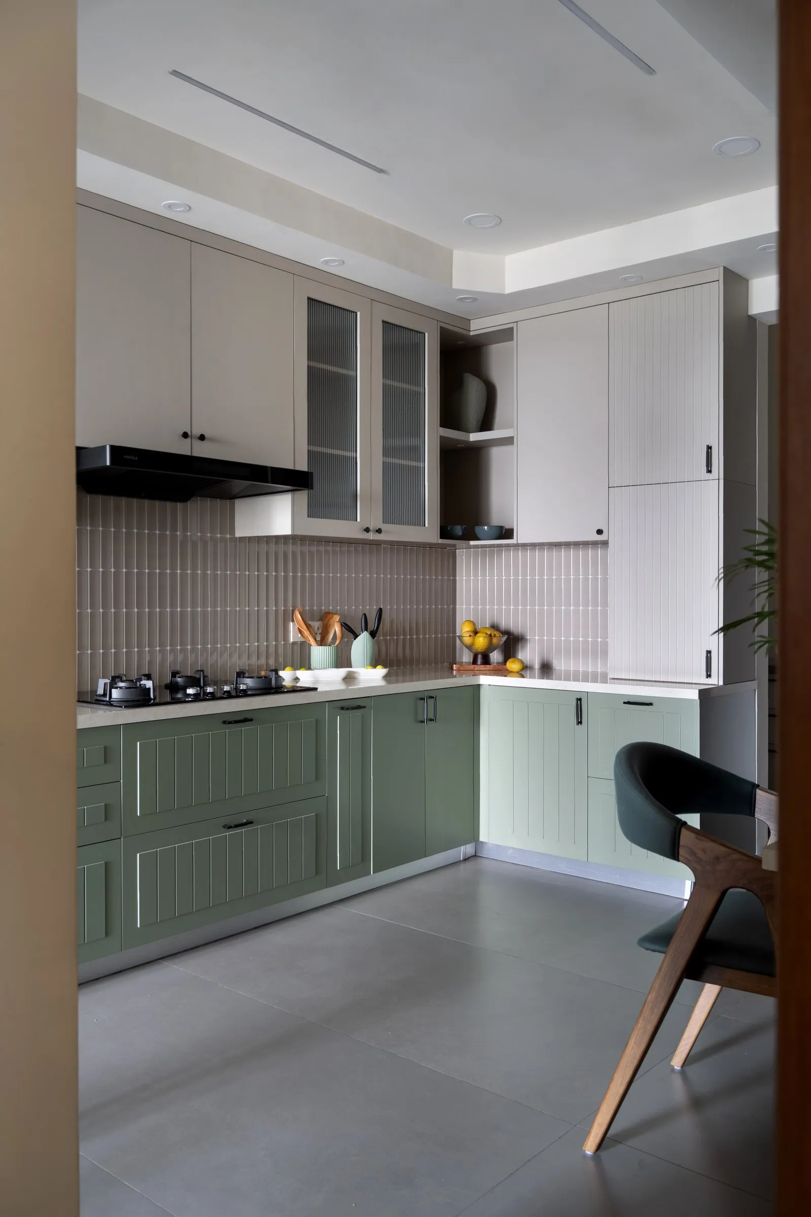 L-shaped kitchen with sage fluted cabinets and a black hood