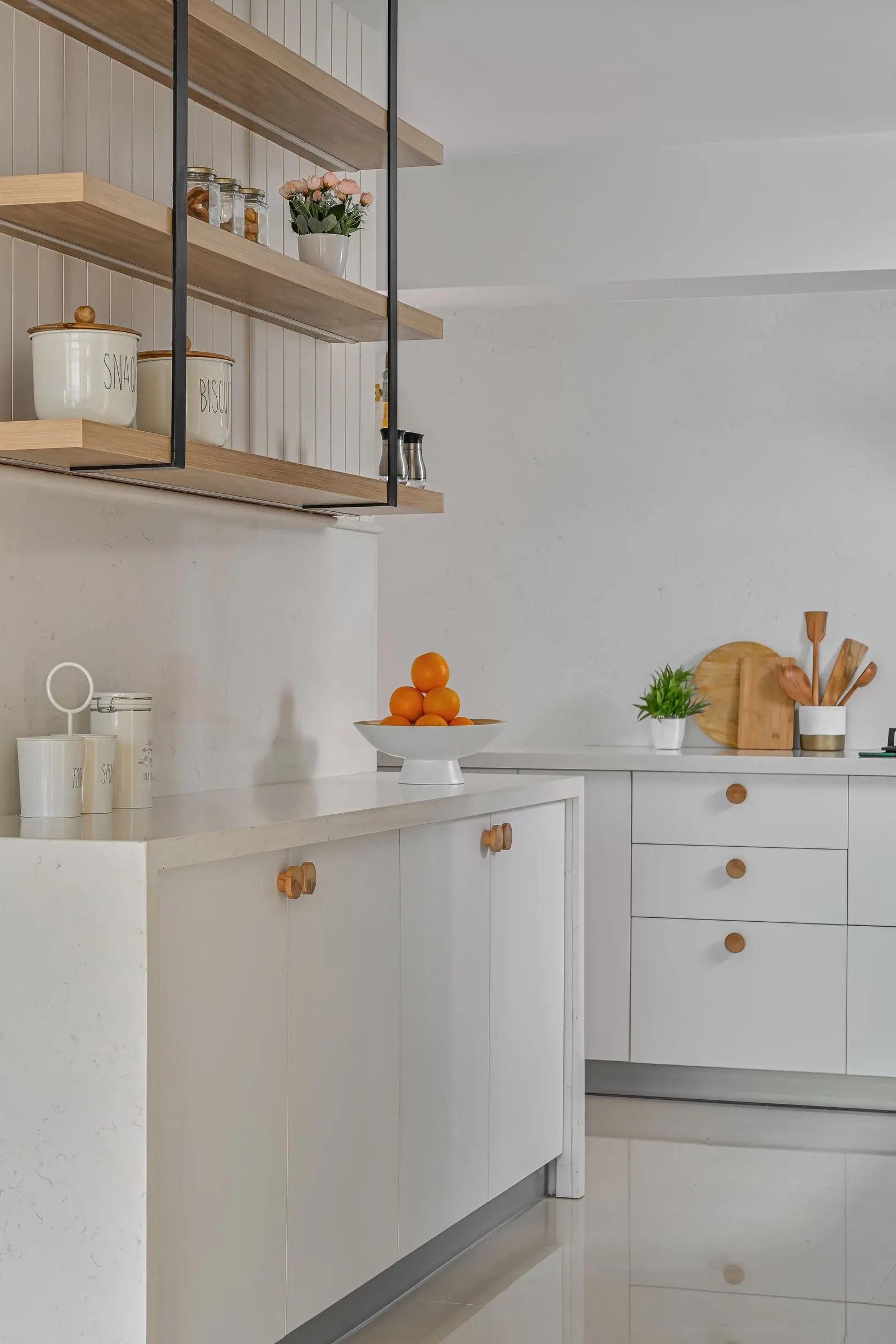 White kitchen with hanging oak shelves and a fruit bowl