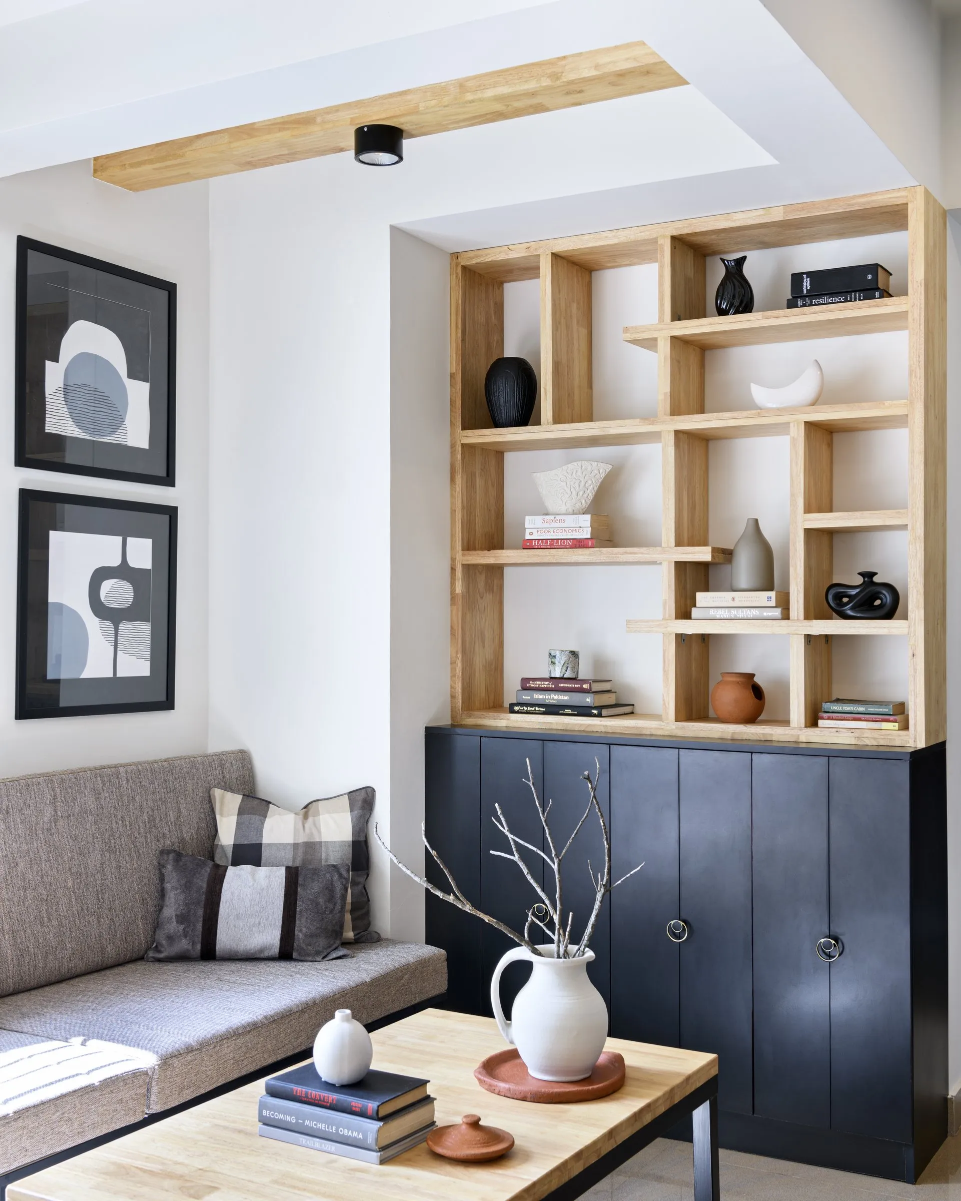 Oak display shelves above a black cabinet beside a sofa