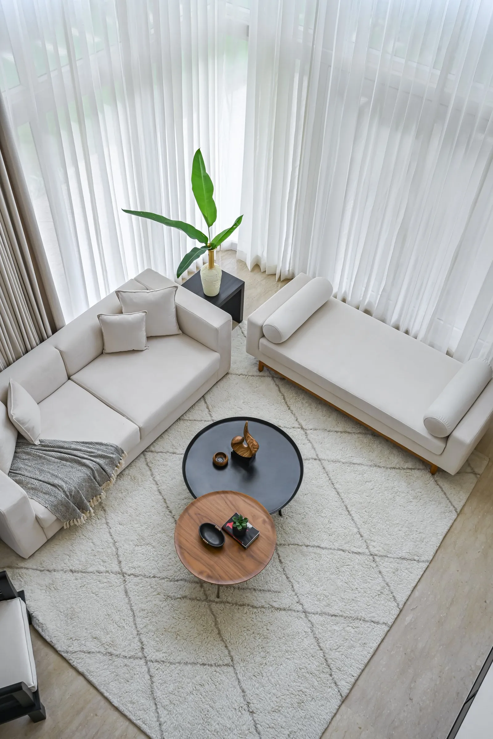 View from above of white sofas and round coffee tables on a patterned rug