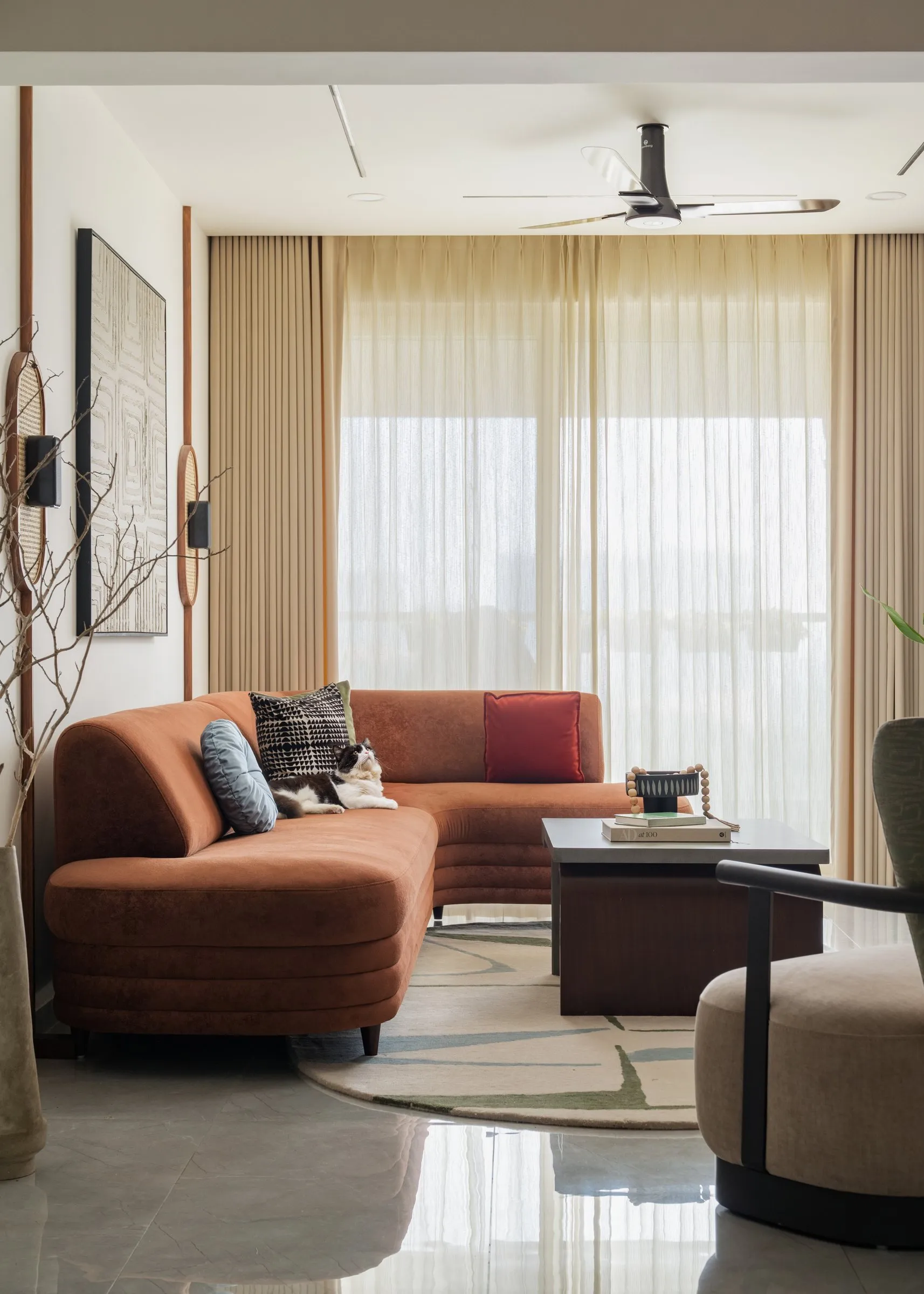 Living room with a curved rust sofa and sheer curtains