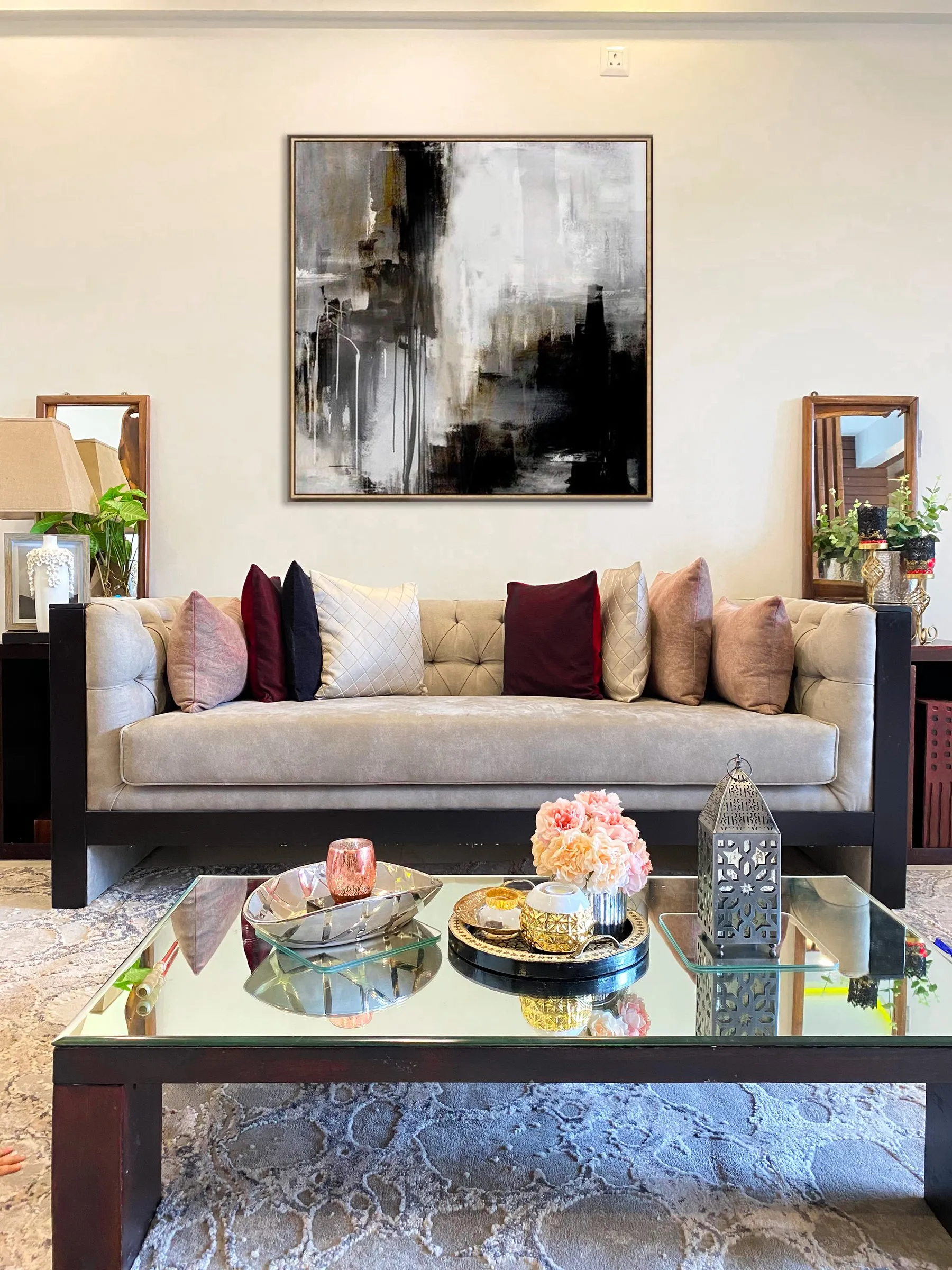 Tufted sofa with blush and burgundy cushions and a mirrored coffee table