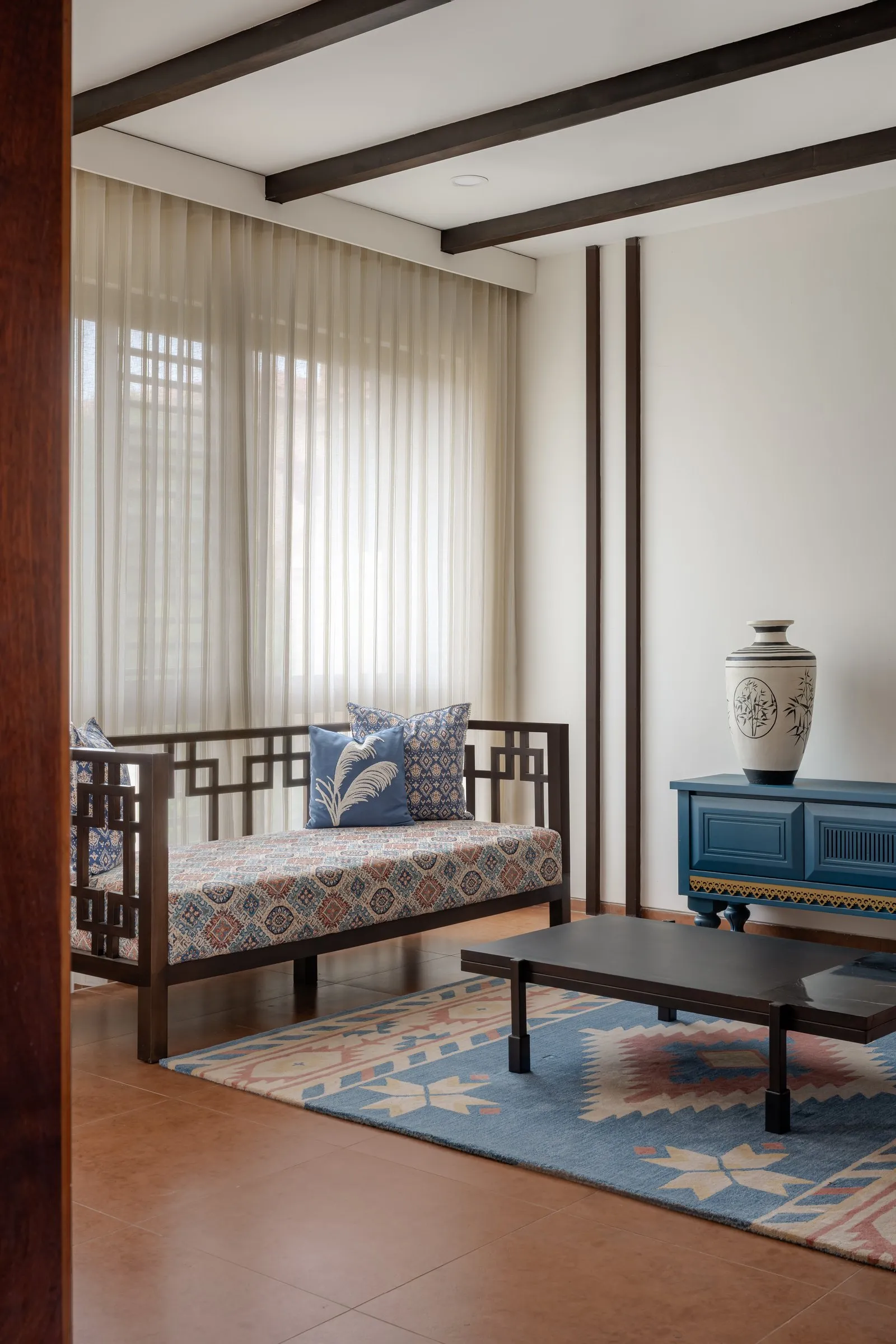Carved wooden daybed with patterned cushions and a kilim rug