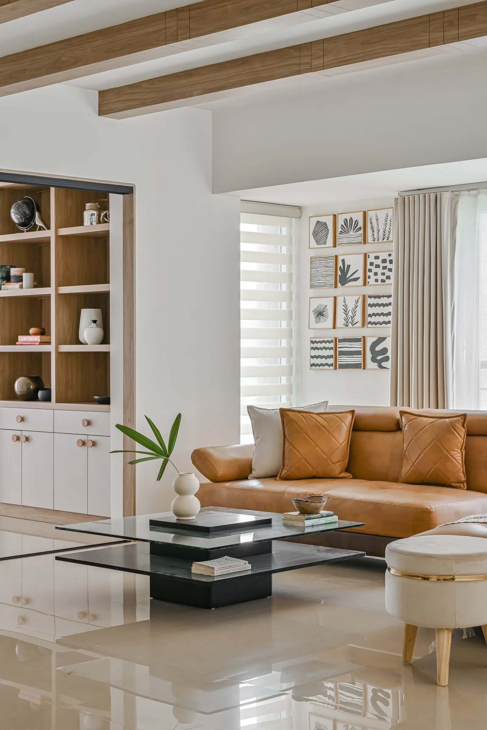 Cognac leather sofa under oak beams with open shelving behind