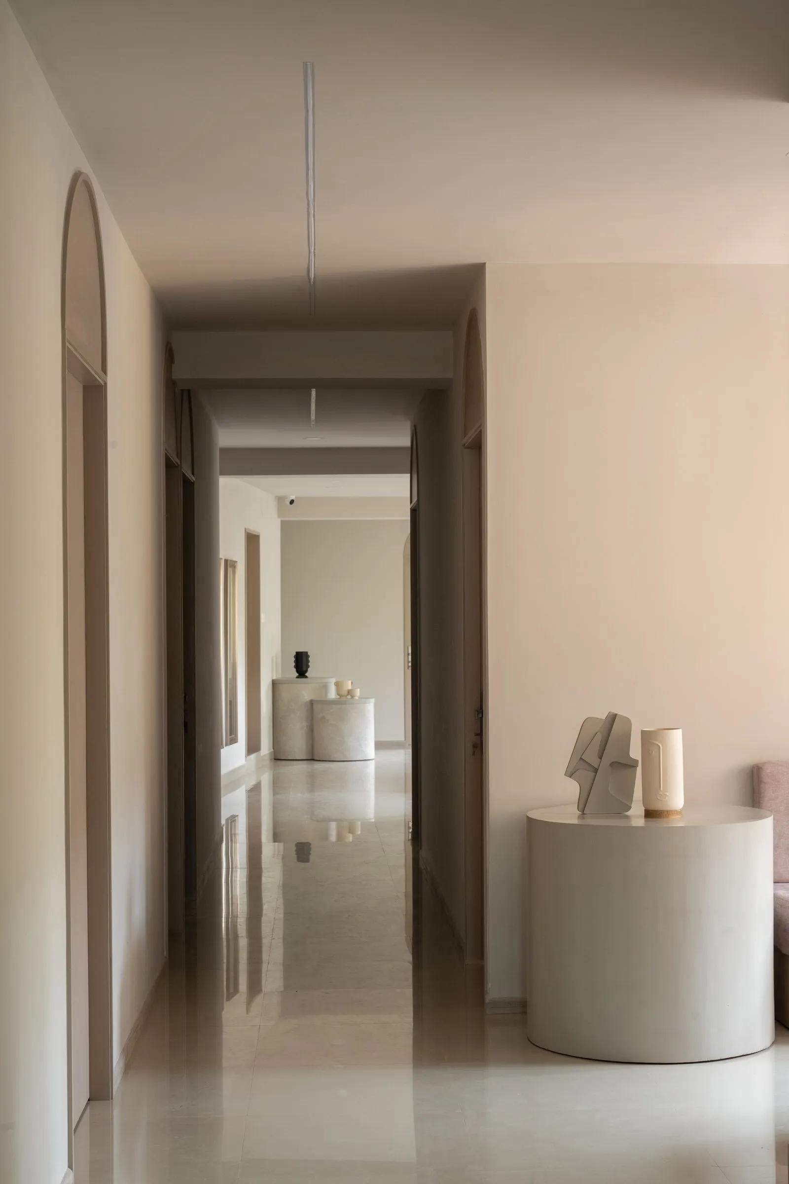 Long corridor with an arched doorway and a round stone table