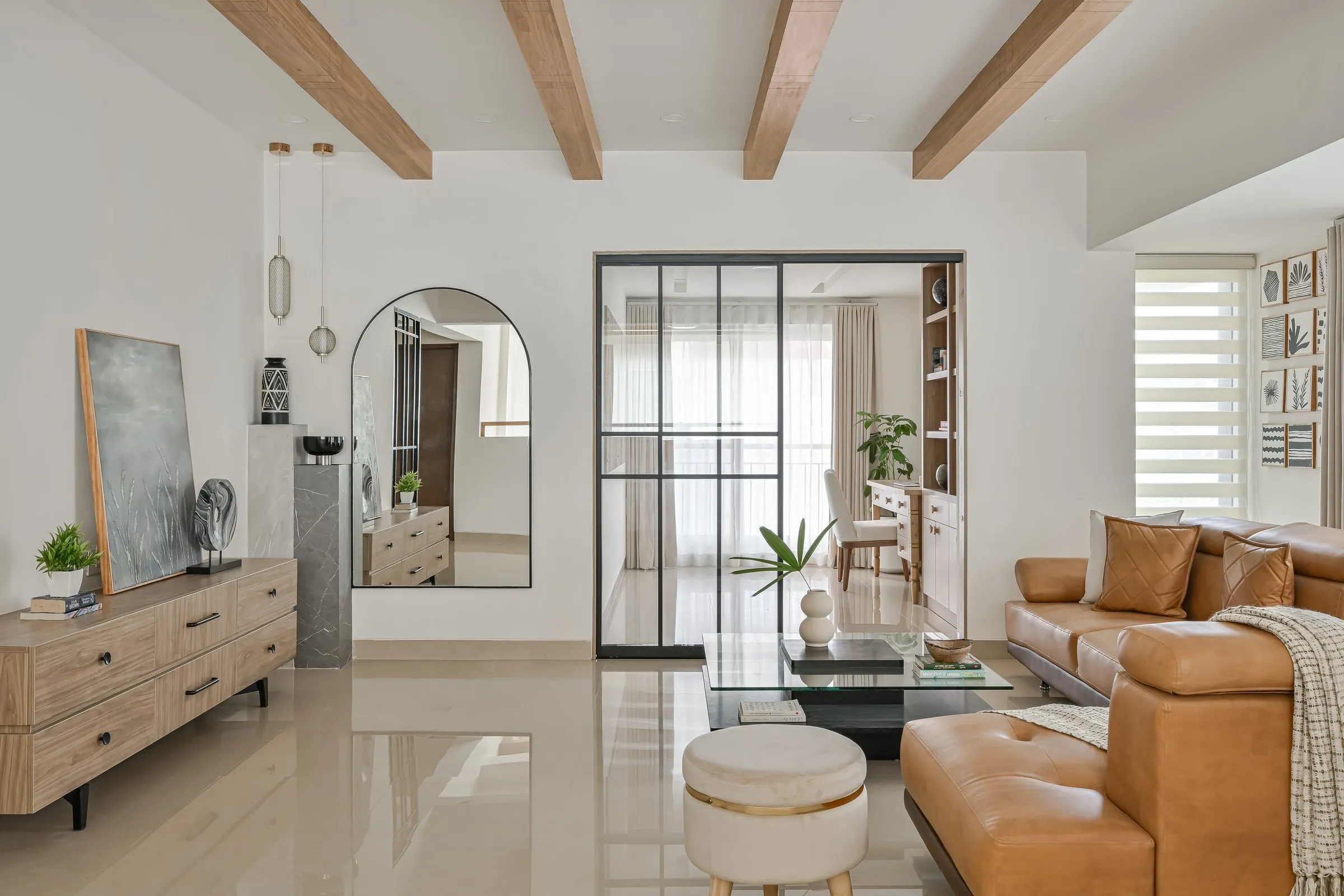 Family lounge with cognac sofas and an arched mirror by the glass partition