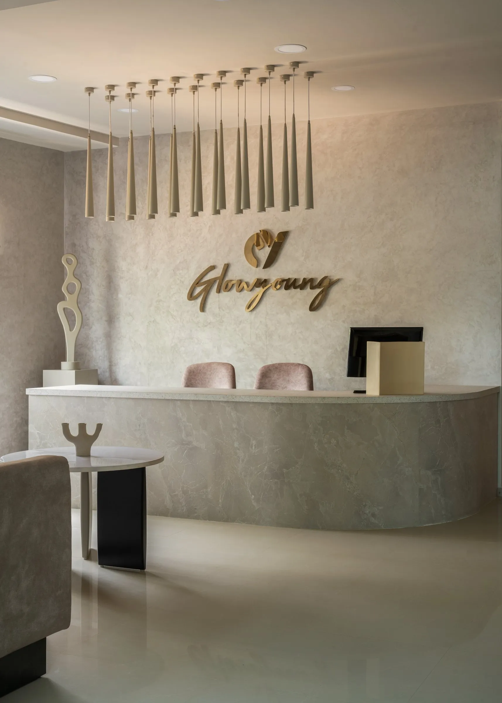 Curved stone reception desk with blush chairs and gold lettering